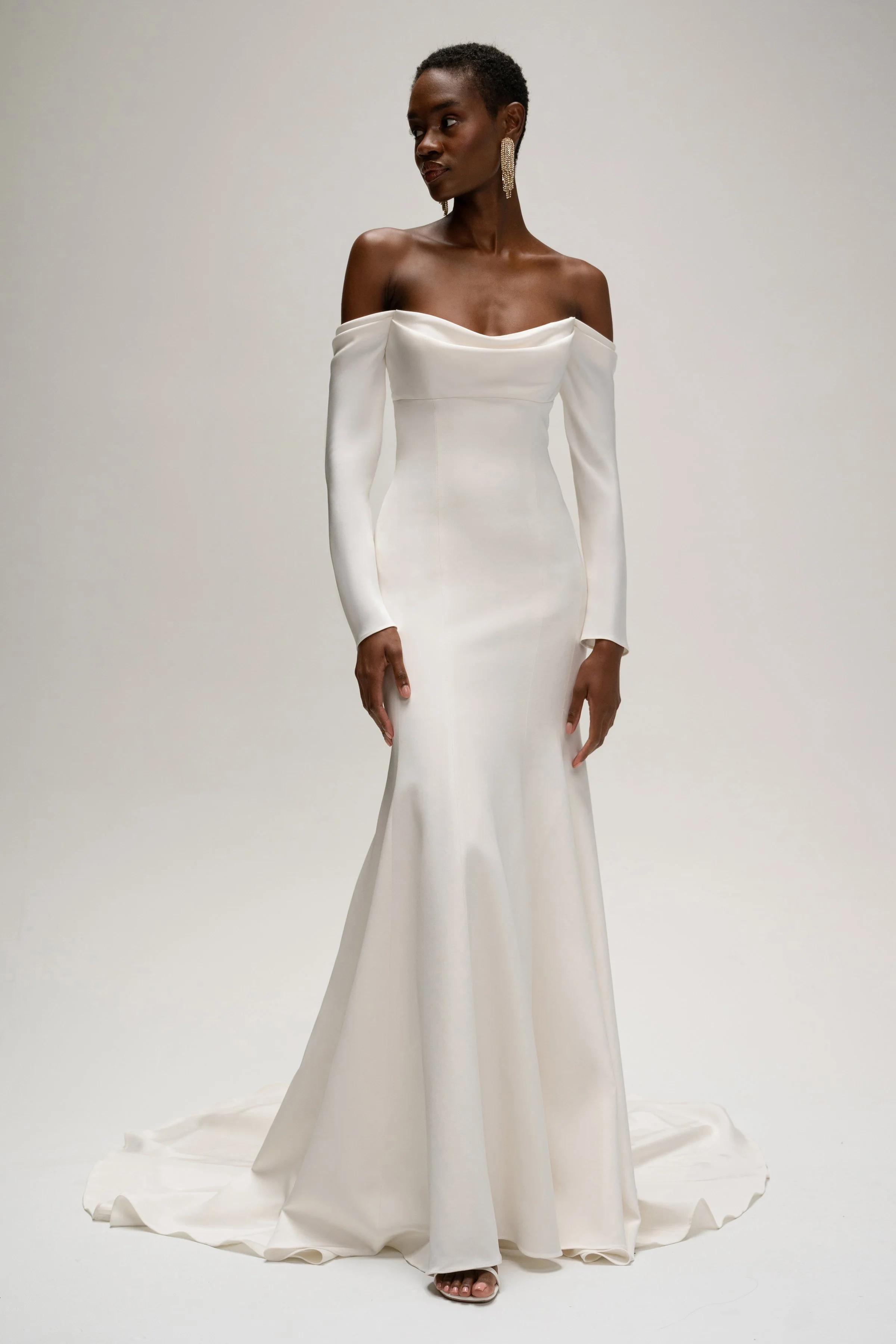 The Jenny Yoo Briar gown is a sophisticated fit-and-flare bridal dress in lustrous silk crepe with a softly draped empire bodice that flatters the décolletage and highlights the shoulders. It features long, slim sleeves and an off-the-shoulder or ele