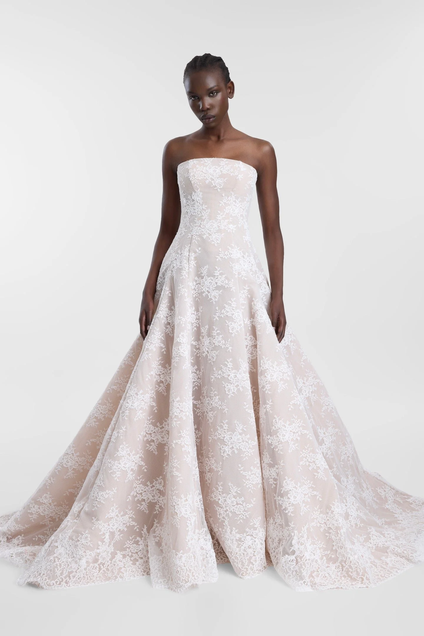 Laced with ethereal romance in KYHA Bride Dalias. A modern take with old-world energy, Dalias is crafted from intricate corded white lace with a chiffon underlay and a scalloped lace trim at the hem. The strapless structured bodice and full skirt and