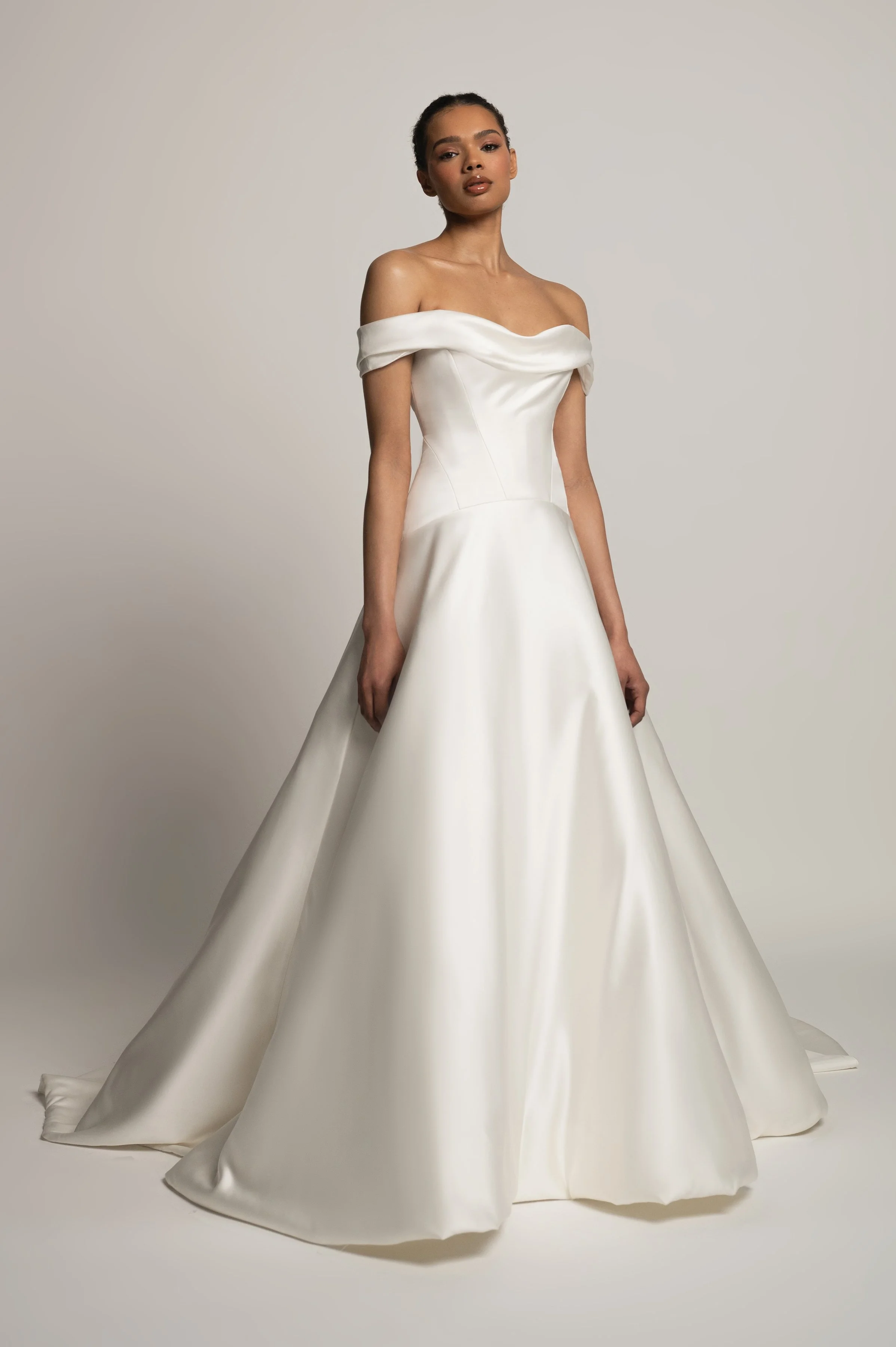The Jenny Yoo Bridal Greer gown, our second collaboration with renowned bridal stylist, Hope LaVine, is as modern as she is timeless. Featuring a softly draped off the shoulder neckline, angled corset seam details, and a curved drop waist, she is stu