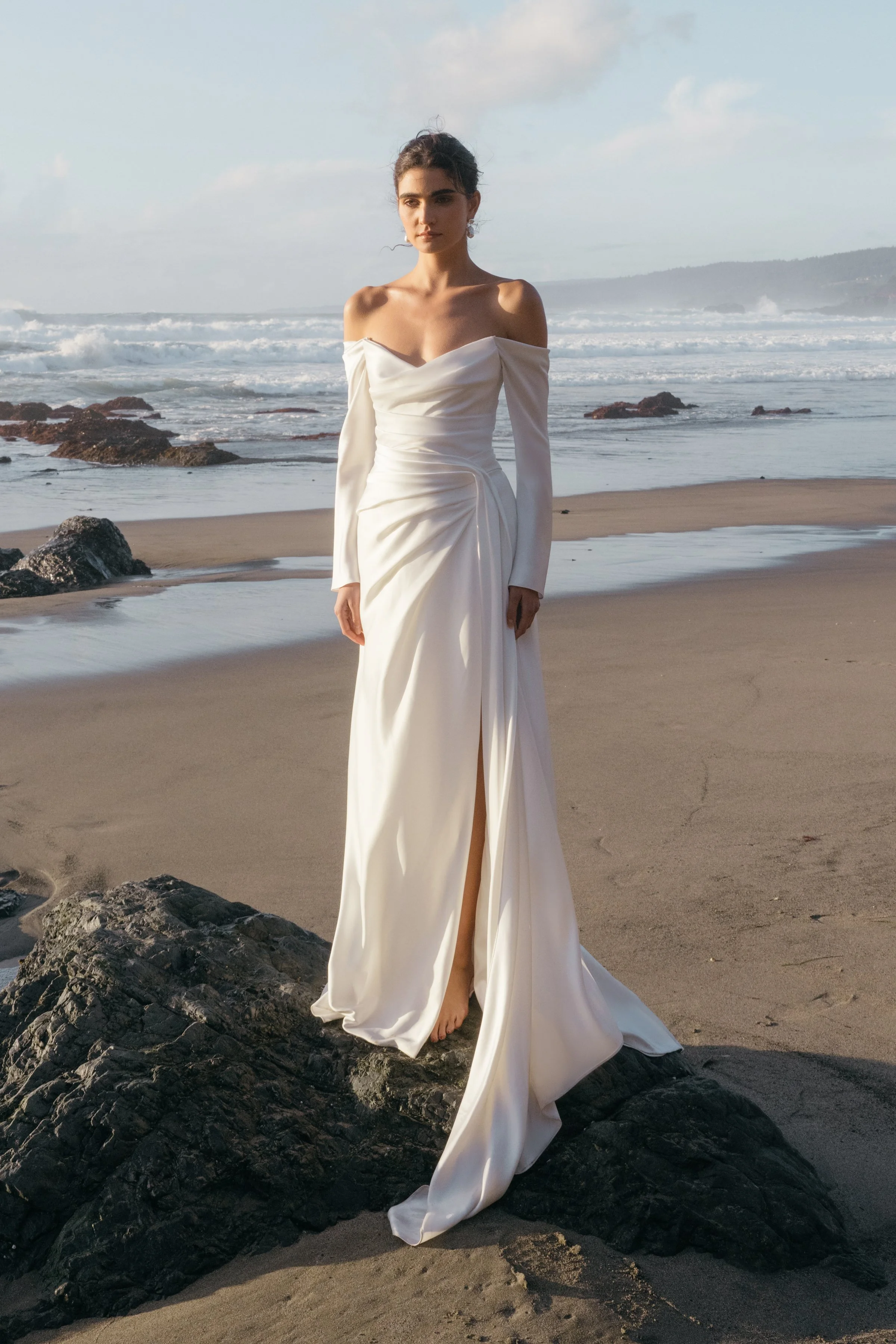 The Jenny Yoo Lana gown is a refined satin wedding dress cut in luminous Barcelona satin with elegant pleating and draping that flatters the figure, and it stands out for its versatile styling with removable long sleeves and optional sash sleeves tha