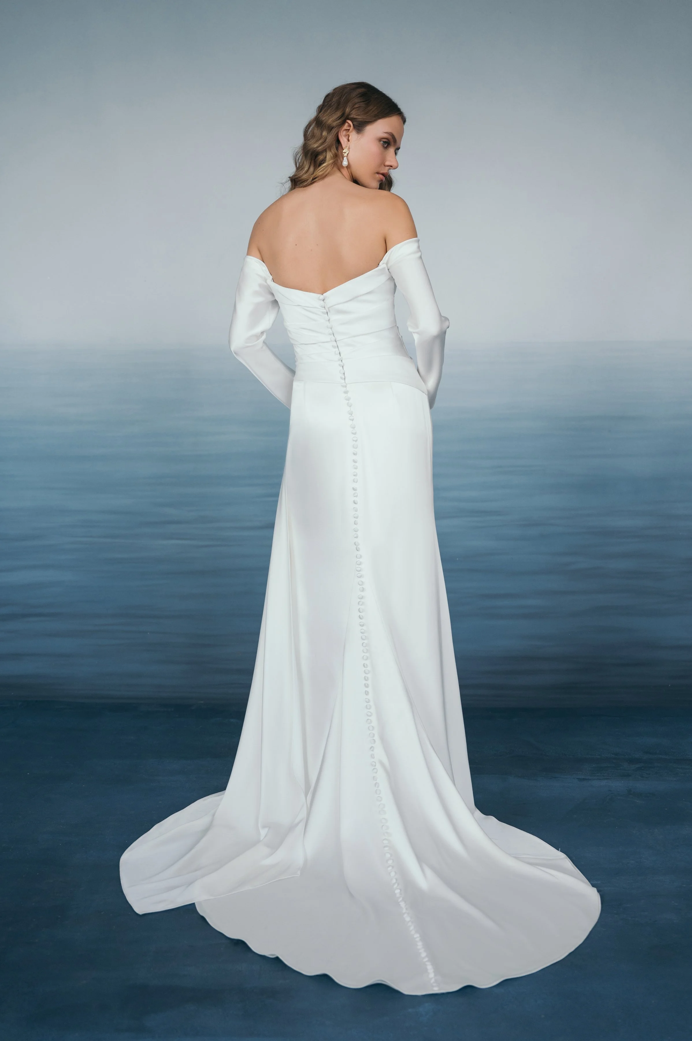 The Jenny Yoo Lana gown is a refined satin wedding dress cut in luminous Barcelona satin with elegant pleating and draping that flatters the figure, and it stands out for its versatile styling with removable long sleeves and optional sash sleeves tha