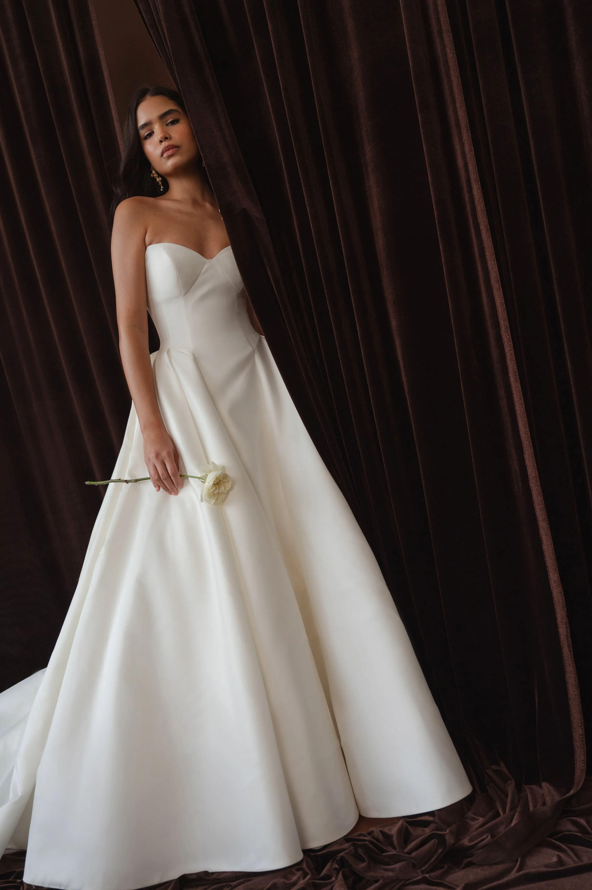 The Jenny Yoo Bridal Colette gown, cut in our light and lustrous Italian taffeta fabric is a clean, yet striking show stopper. Intricate seam details sculpt a bustier bodice and subtle drop waist silhouette. Pleats in the ball skirt create dramatic v