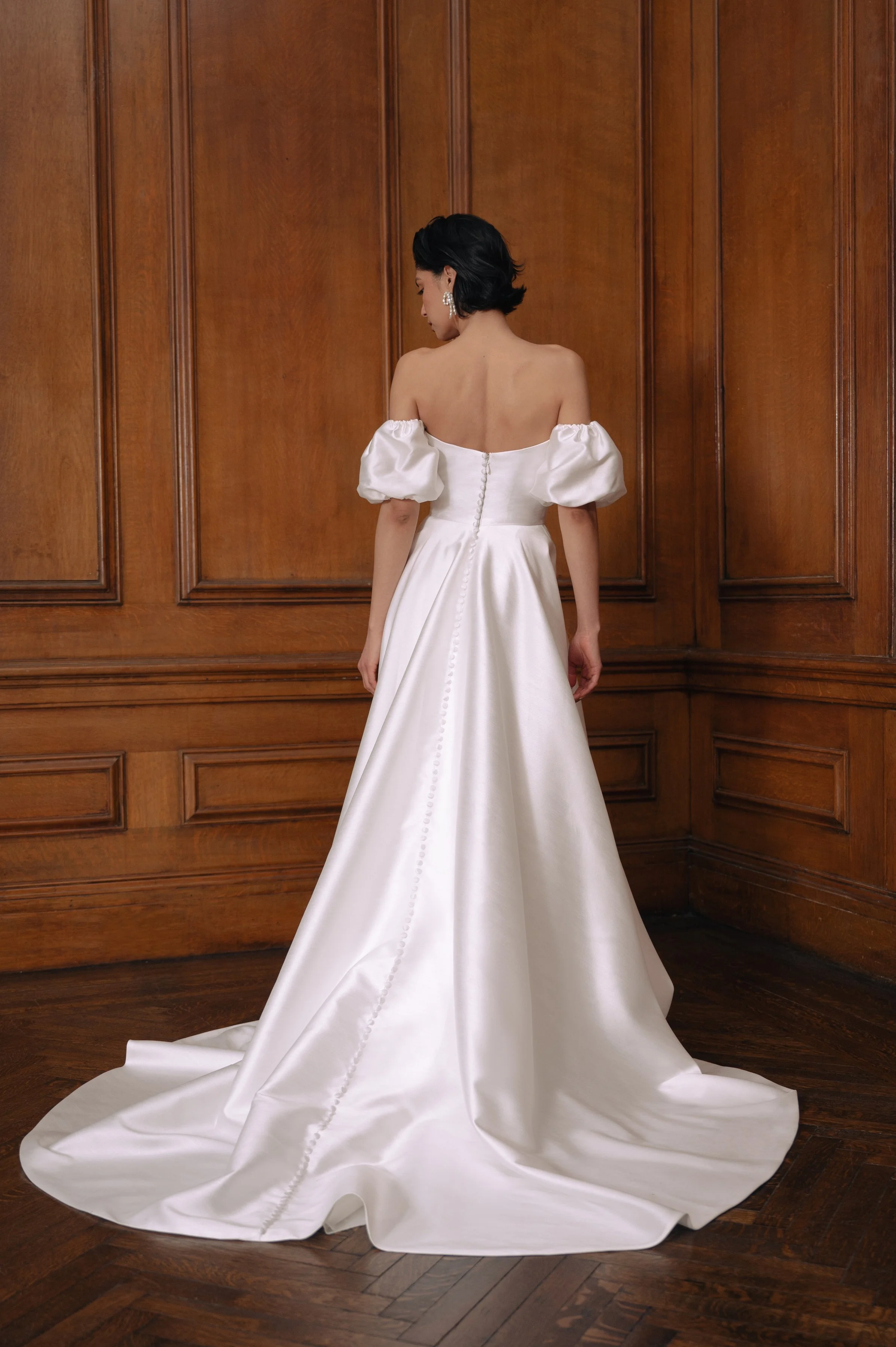 The Jenny Yoo Marisol gown is a romantic satin ball gown with a beautifully draped bodice and a sultry, sculpted cowl neckline that feels effortlessly feminine. It features a full skirt interrupted by a flattering slit and comes with detachable puff 
