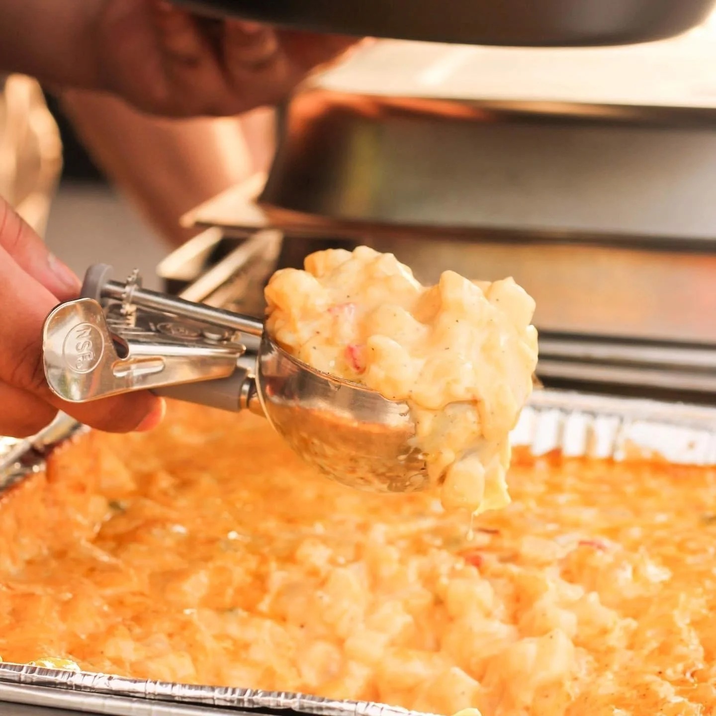 Scoop of baked mac and cheese being served from a tray