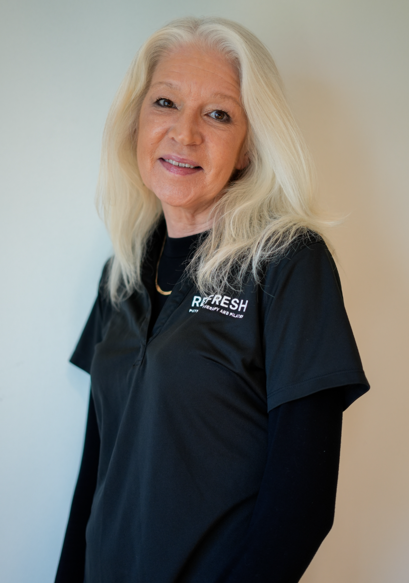 A woman with blonde hair and glasses taking a selfie in front of a wall with blue neon text. The text reads, 'You're exactly where you'.