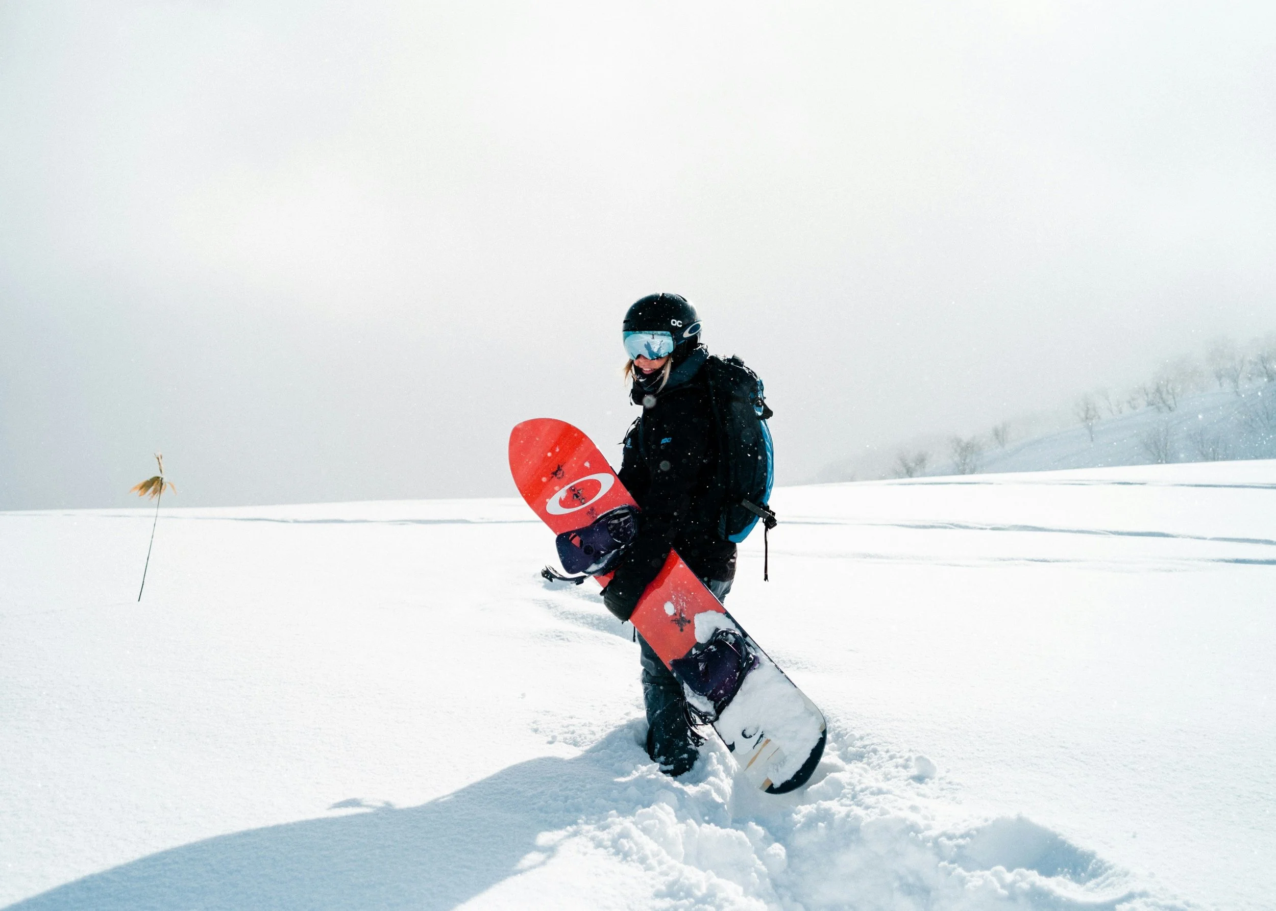 Photo of a snowboarder standing ion deep snow holding their snowboard