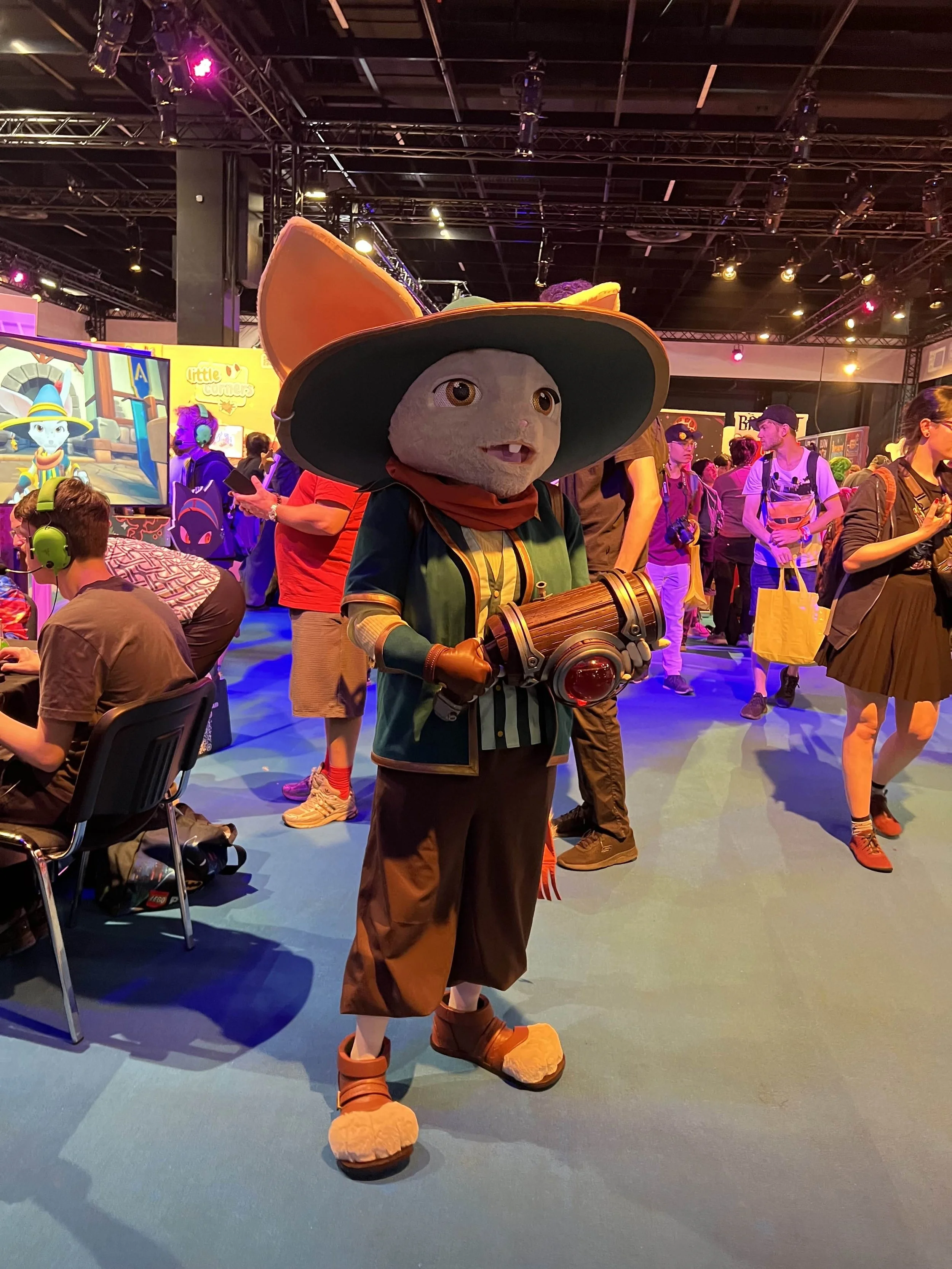 A cosplayer of the main character of the roguelite game Brew. Brew came out in 2025 and the cosplay is standing in the indie arena booth in Gamescom 2025