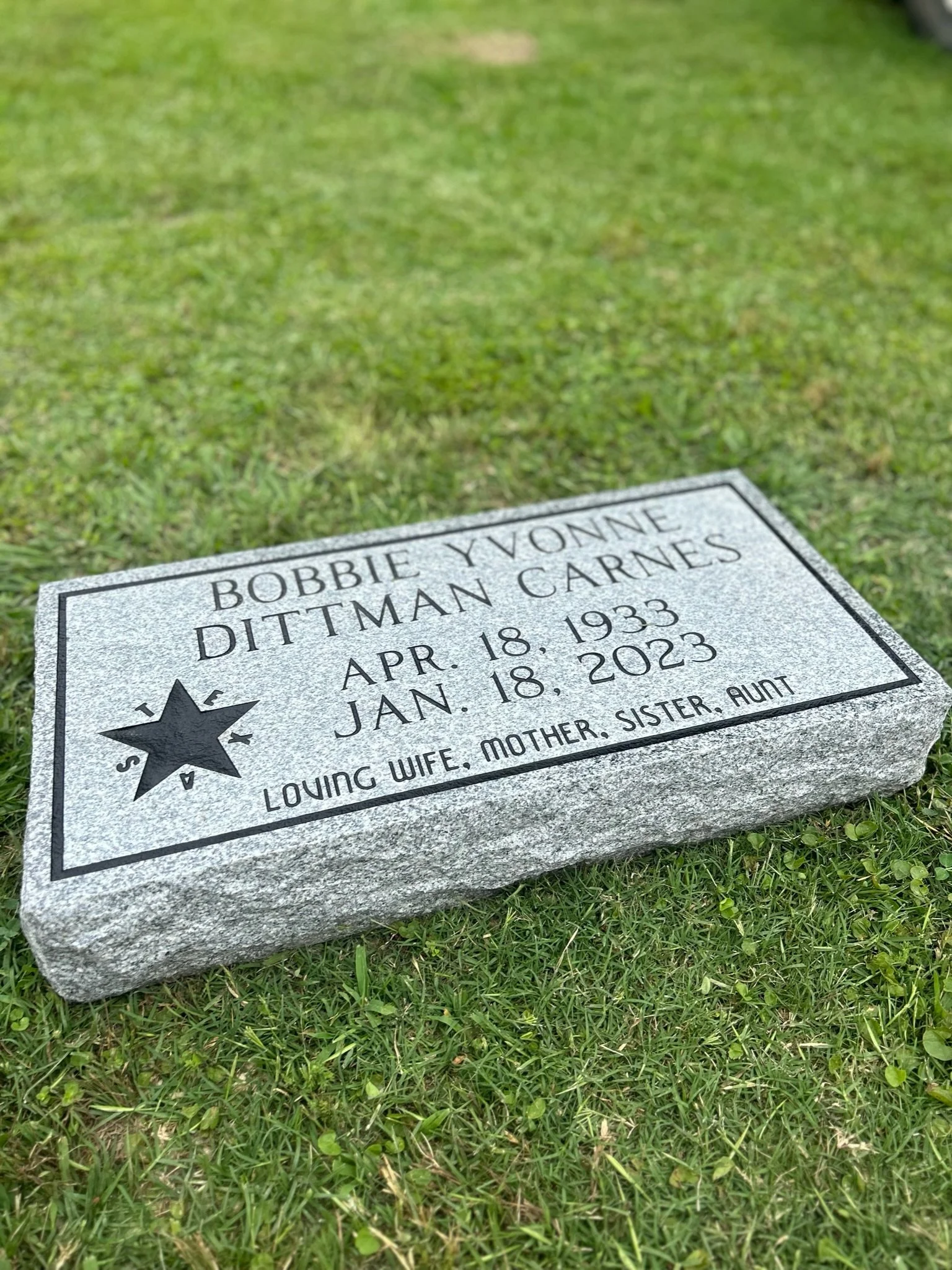 Granite gravestone for Bobbie Yvonne Dittman Carnes, born April 18, 1933, died January 18, 2023, engraved with a star and the words "Loving wife, mother, sister, aunt" on a grassy ground.