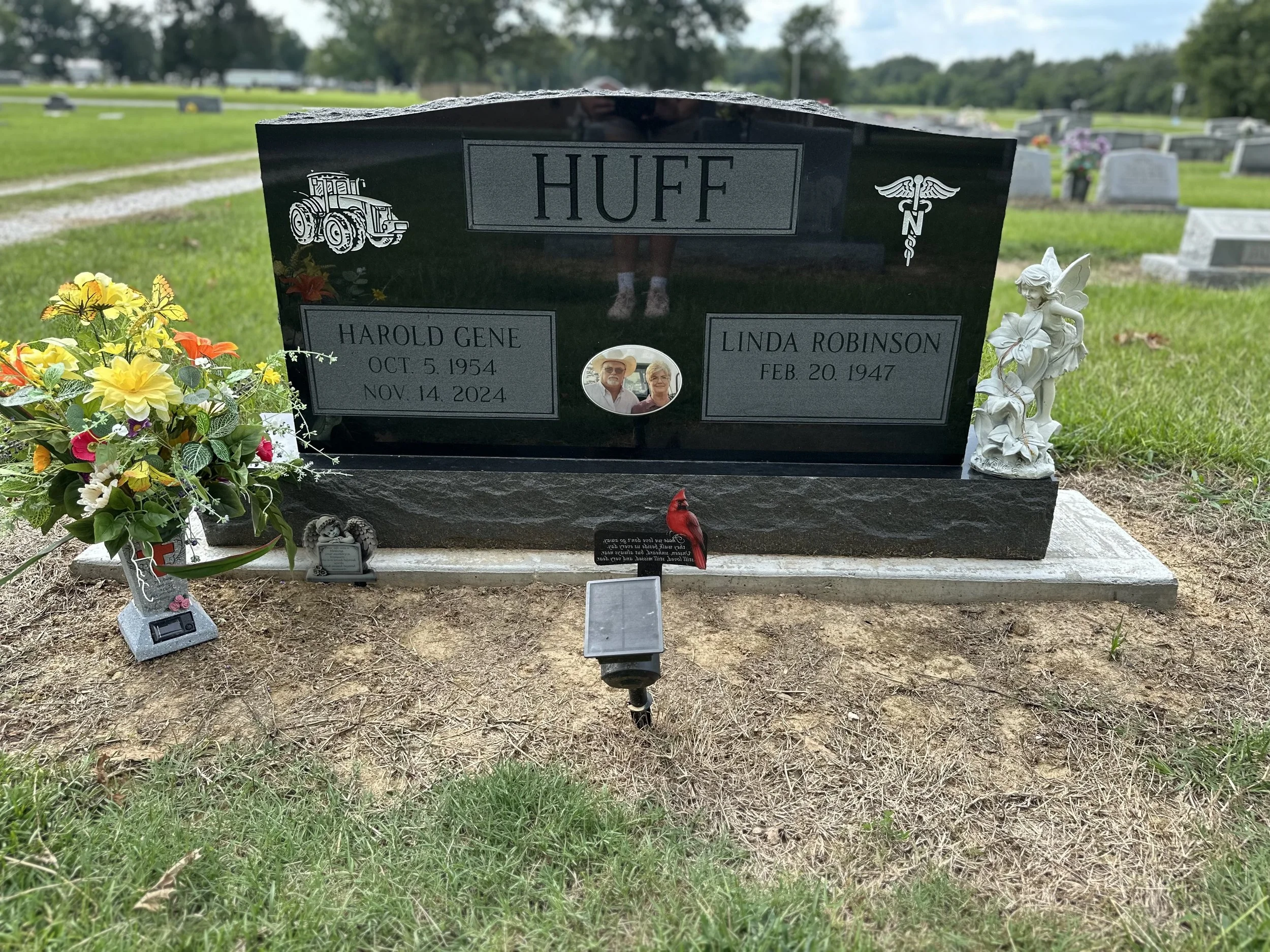 A black granite headstone at a cemetery honoring Harold Gene Huff (October 5, 1954 - November 14, 2024) and Linda Robinson (February 20, 1947). The headstone features a tractor and medical symbol, with a small photo of an elderly couple. There are co