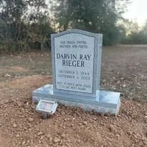 Gravestone for Darwin Ray Rieger with personal details and floral arrangements in a cemetery.