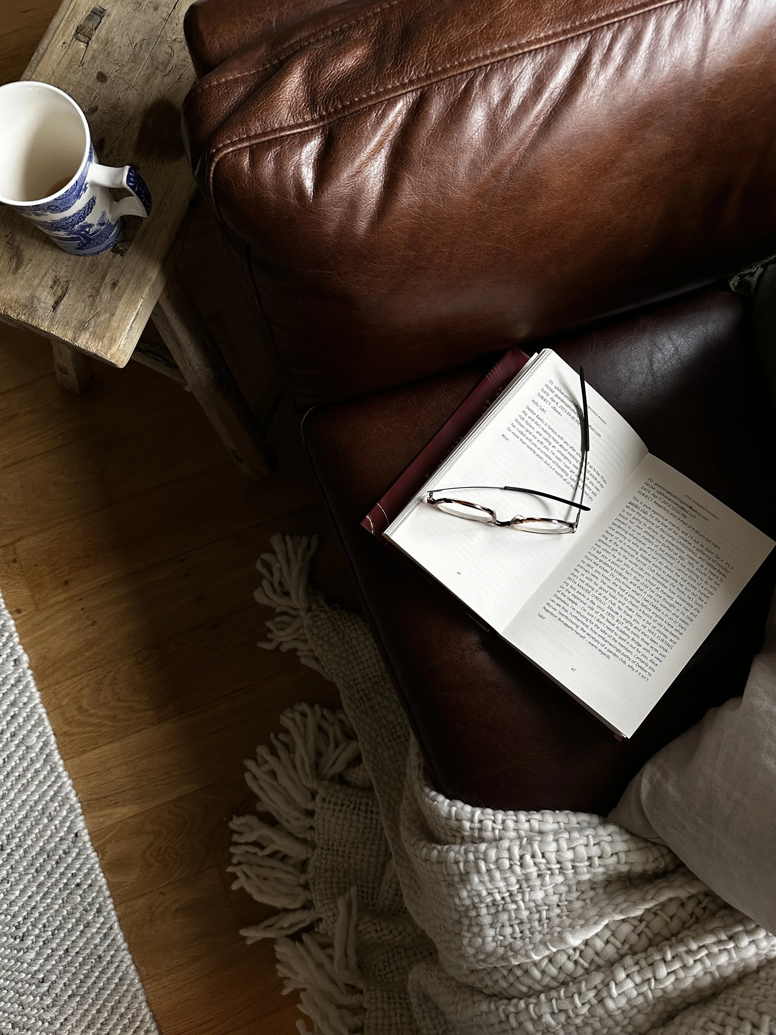 open book reading glasses on brown leather armchair