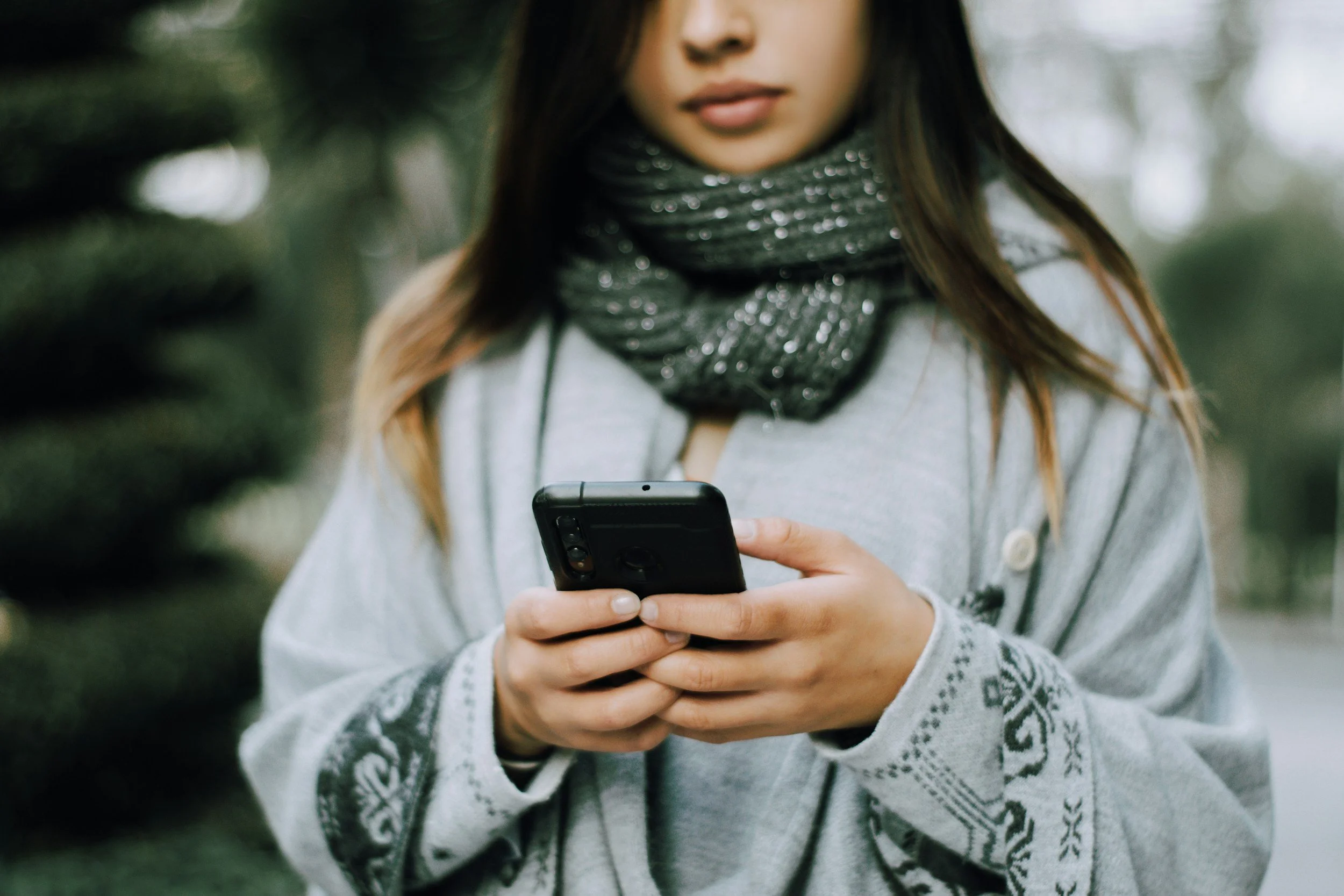 Asian teen girl looking down at her cell phone.