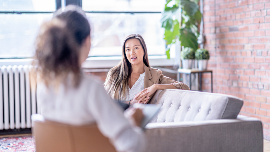 Adult woman sitting on a couch talking to her therapist