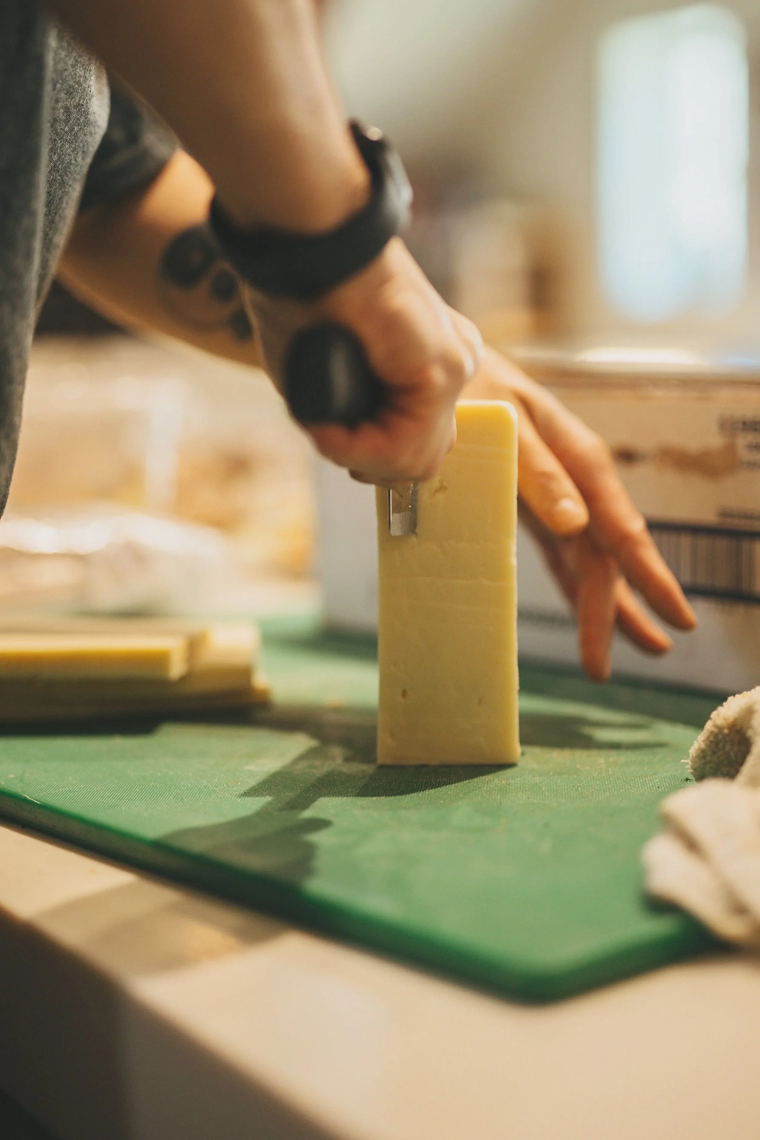 A grocery store shelf with cereal boxes, green tea, coffee filters, snacks, and canned goods, with vintage artwork of children and a woman hanging on the wall behind.
