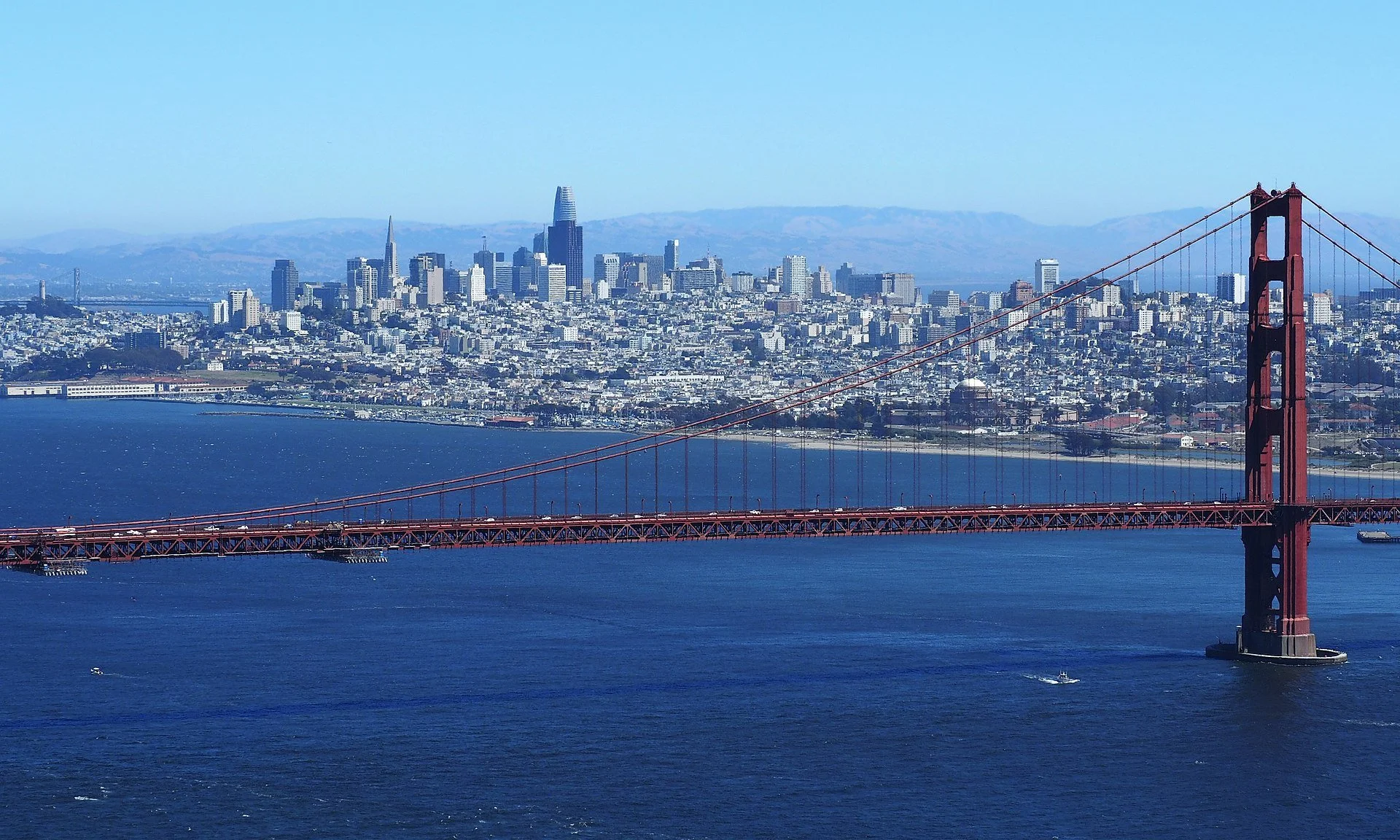 Aerial view of San Francisco city skyline with the Golden Gate Bridge in the foreground and San Francisco Bay below.