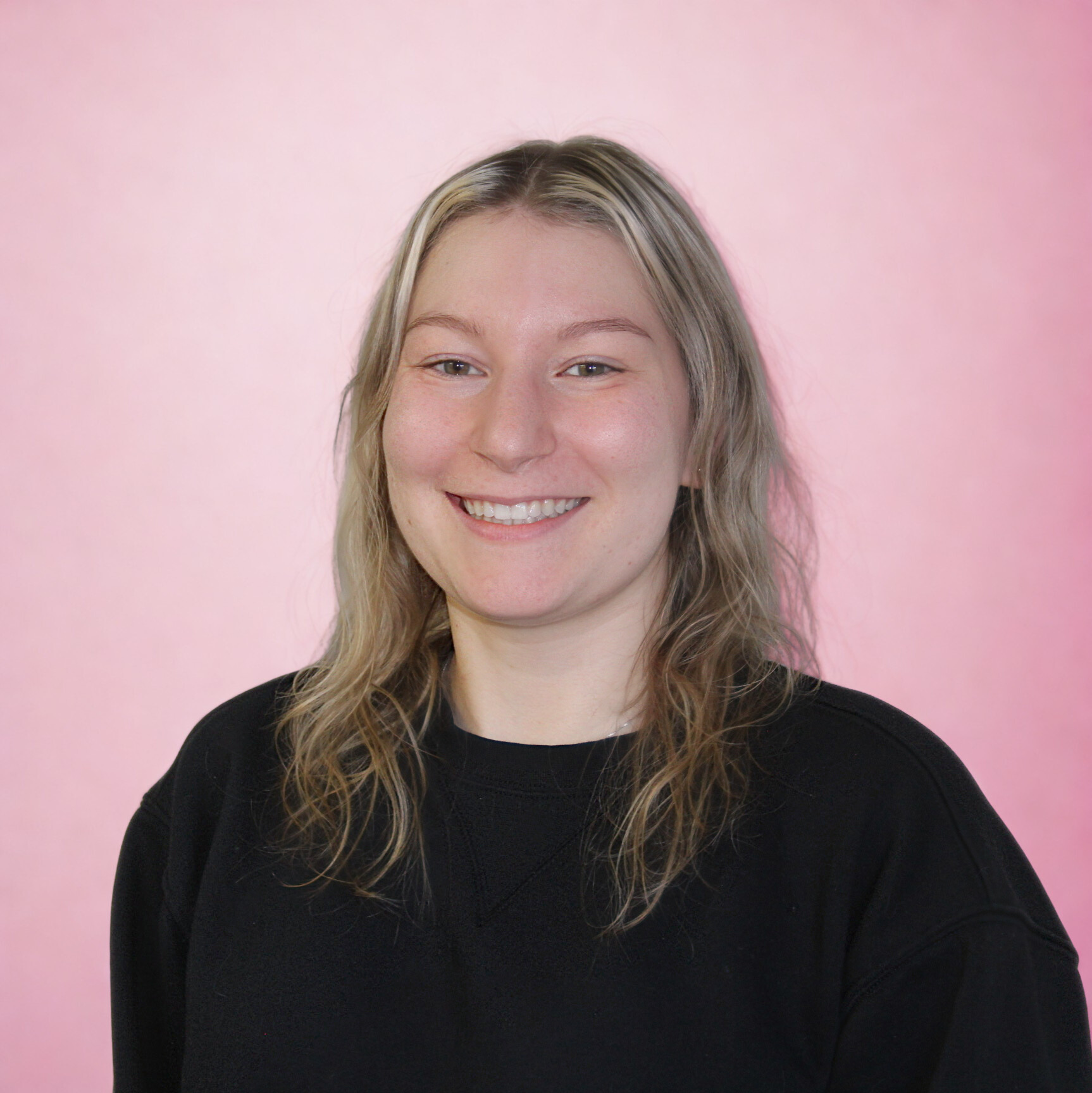 A woman with blonde, wavy hair smiling against a pink background therapist Wyomissing Clear Water Wellness mental health provider