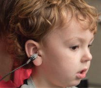 Young child with earbud in ear, partial profile view.