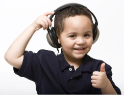 Young boy smiling, wearing headphones, and giving a thumbs-up gesture.