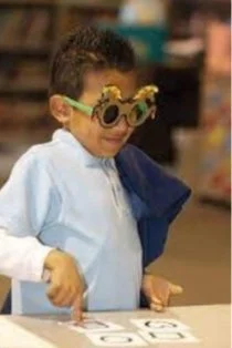 Child wearing novelty sunglasses with numbers on table
