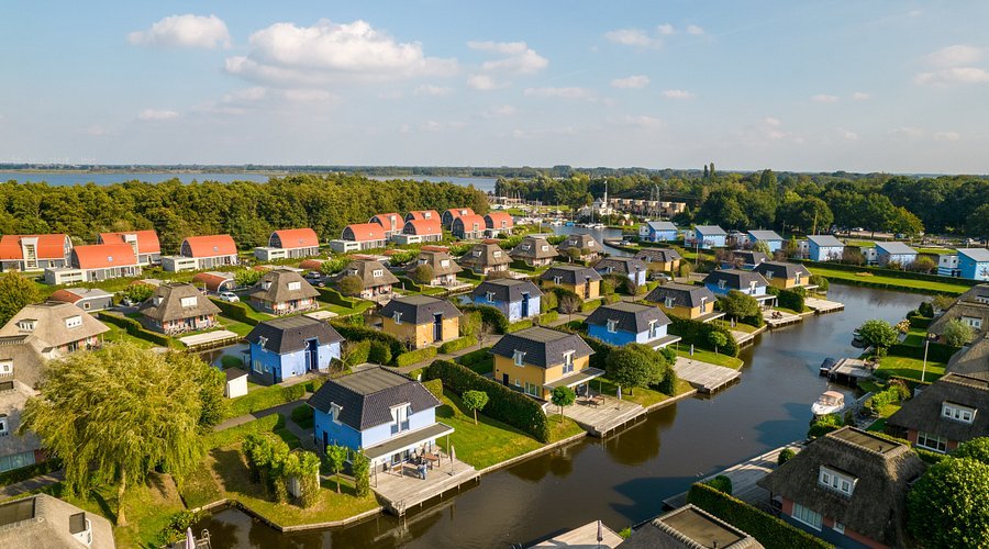 Een overzicht van kleurrijke huizen langs een kanaal in een rustige wijk, natuur en water in de omgeving.