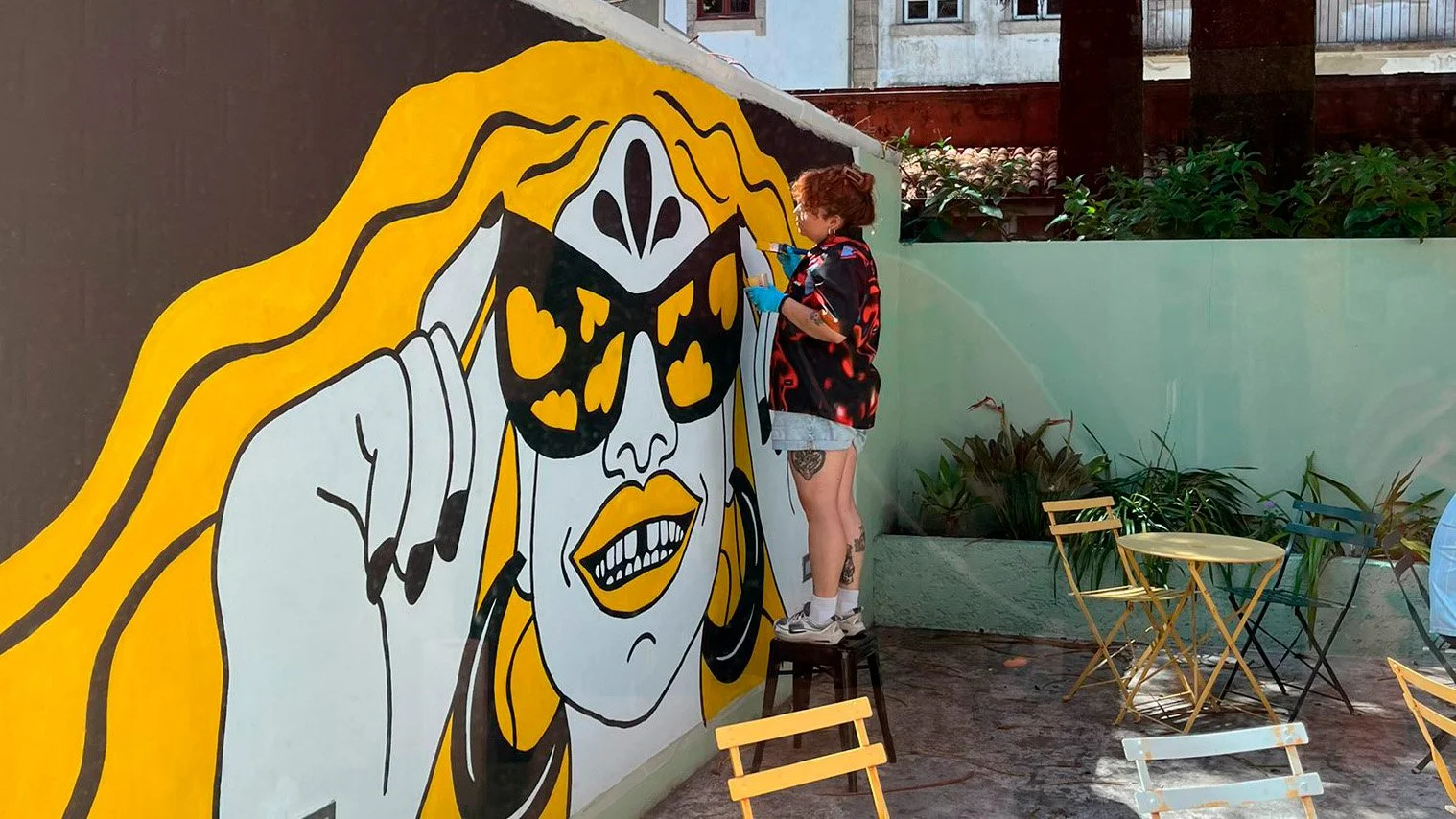 Wide angle of the artist painting the finishing touches on the Peloton Café mural