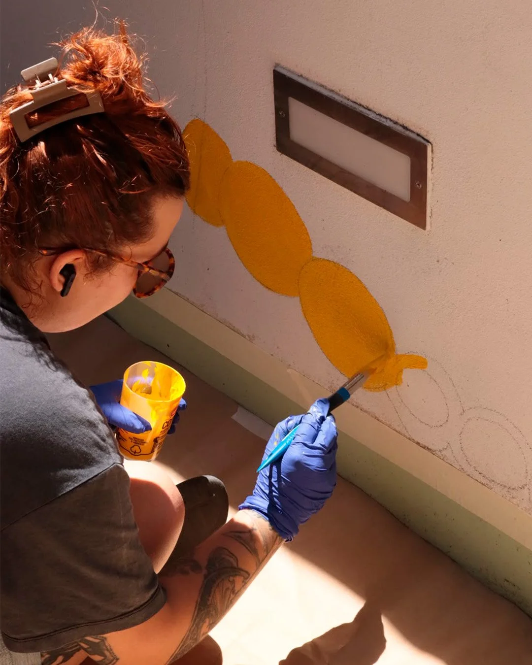 Close-up of the artist painting a detail of the Peloton Café mural