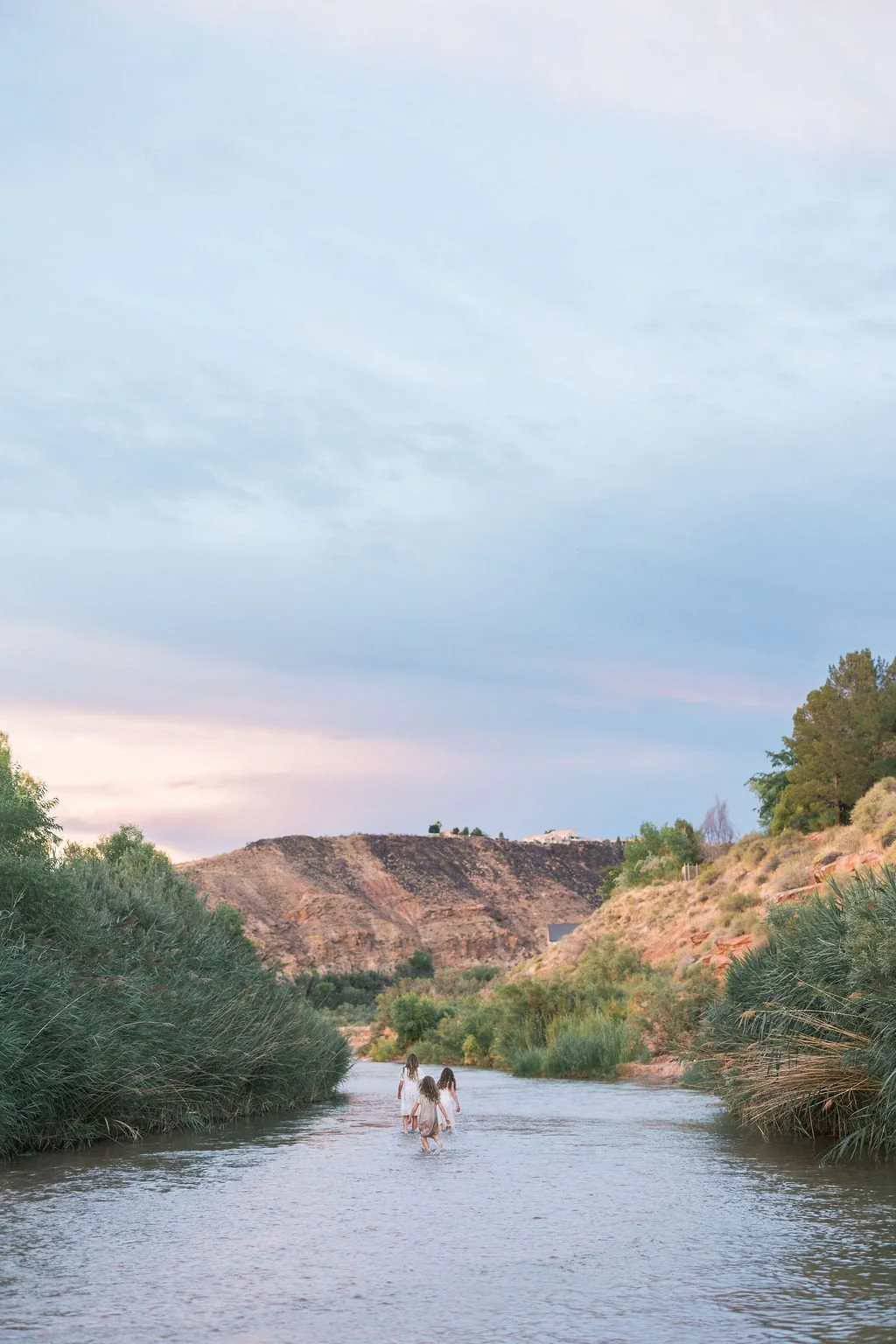 Adventure family photography capturing a family exploring and playing together in a scenic Southern Utah river. This unique St. George family photoshoot combines breathtaking landscapes, genuine connection, movement, and candid moments to create unfo