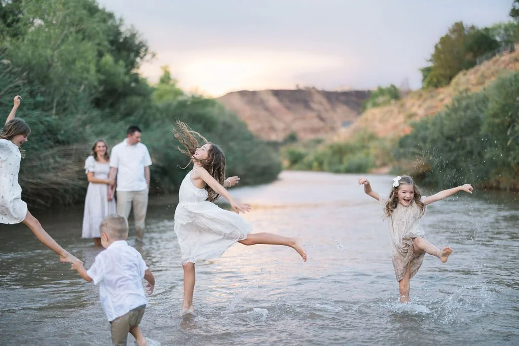 Lifestyle family photography capturing playful, authentic moments as a family splashes and explores together in a Southern Utah river. This St. George family photoshoot celebrates genuine connection, movement, laughter, and the beautifully imperfect 