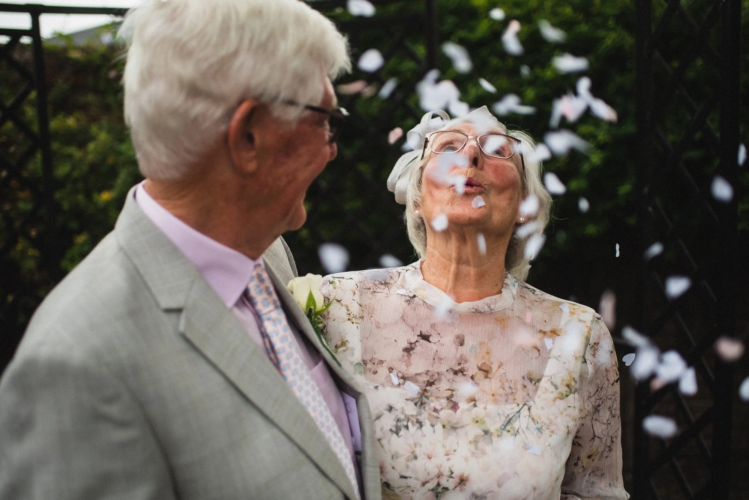 Un couple âgé souriant sous une pluie de confettis.