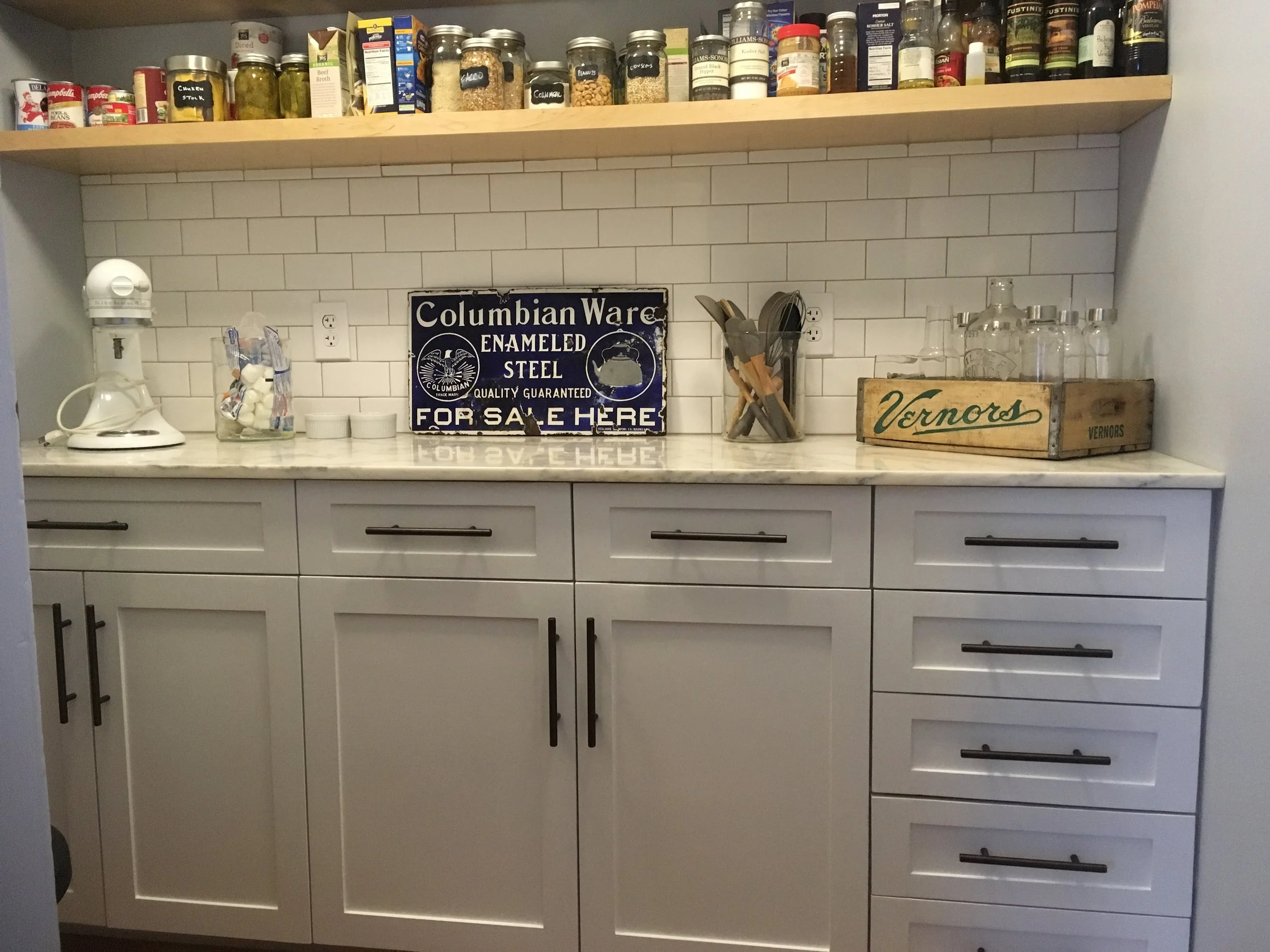 Site built cabinets with floating maple shelves and subway tile