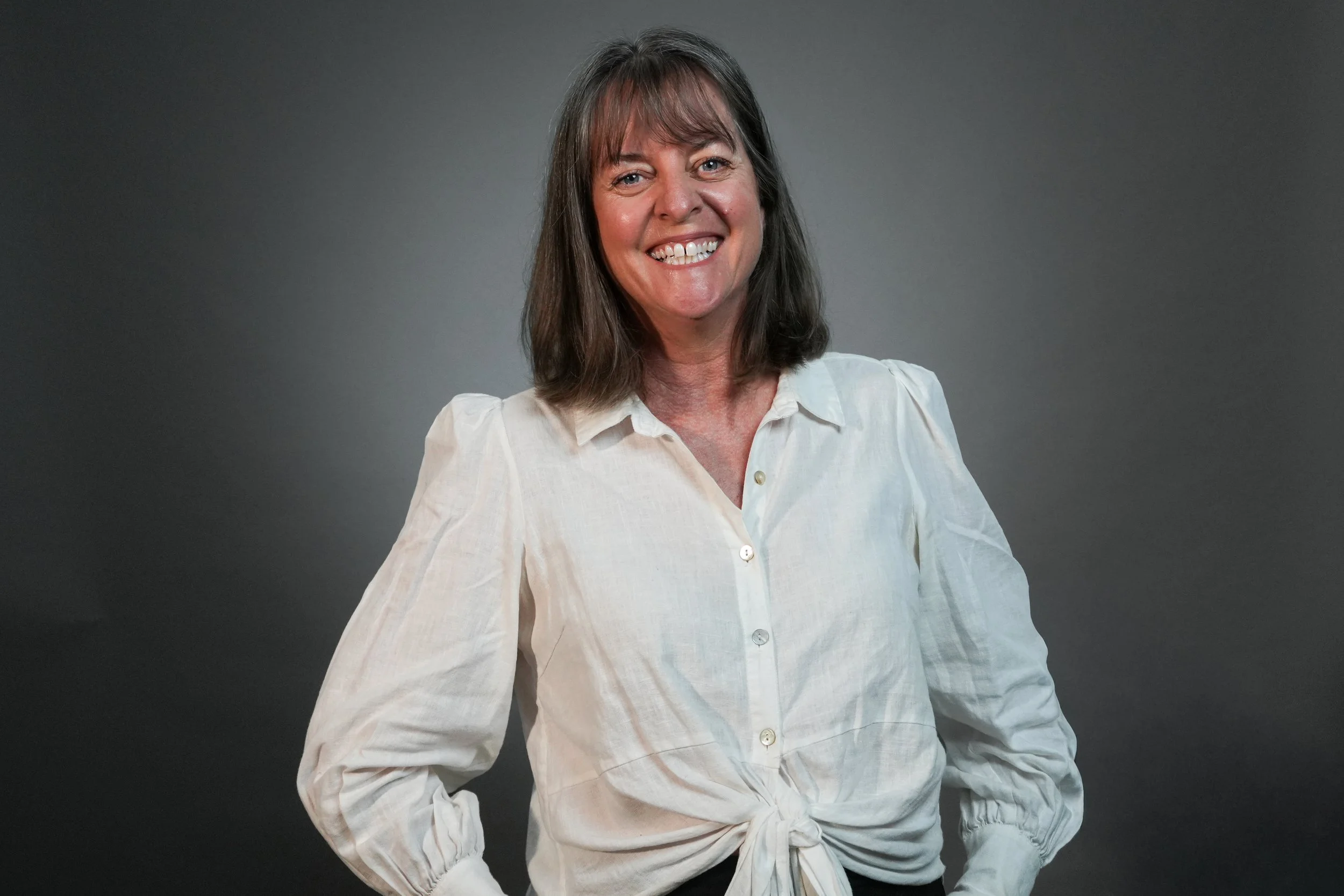 Smiling person in a white shirt against a gray background