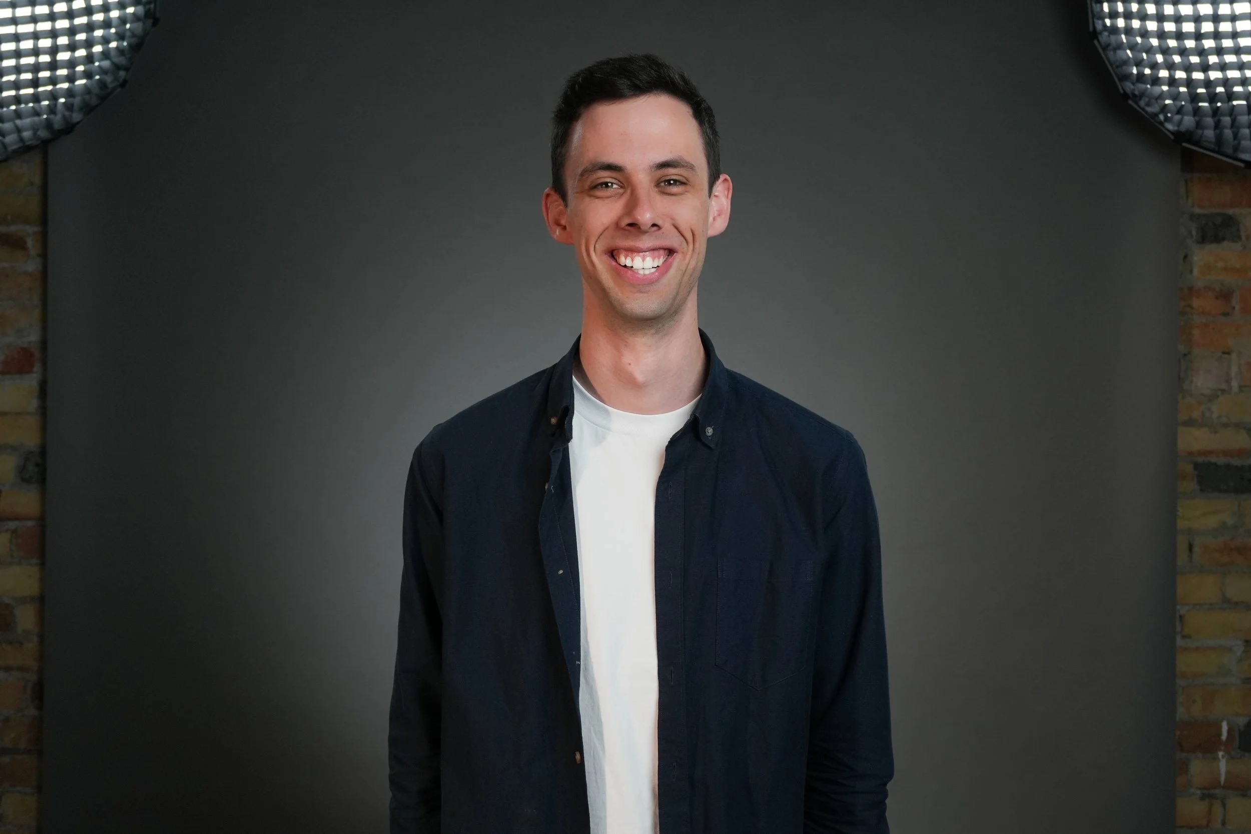Person smiling in casual clothing against a gray background.
