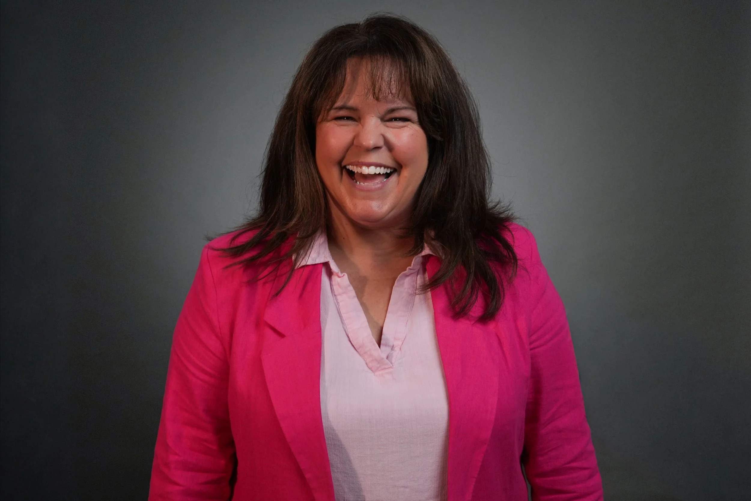 Smiling person in blue striped shirt against gray background.