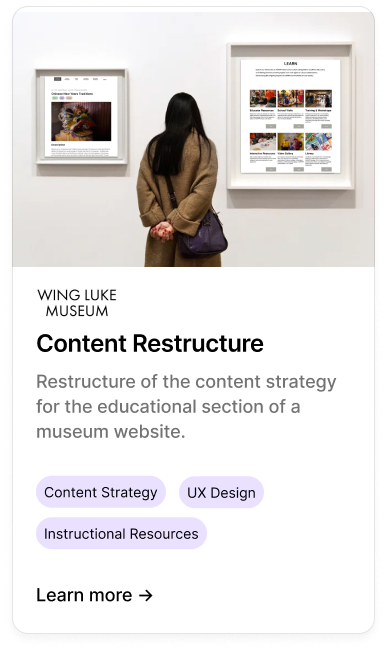 A woman with black hair and a brown coat is standing in front of a museum display wall, looking at two framed digital screens showing museum website content. The wall has a sign that reads 'Wing Luke Museum' and a section titled 'Content Restructure' with a description and tags for 'Content Strategy,' 'UX Design,' and 'Instructional Resources.'