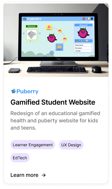 Computer screen displaying the Puberry gamified student website with colorful characters and progress levels, surrounded by a keyboard, mouse, and external device on a desk.