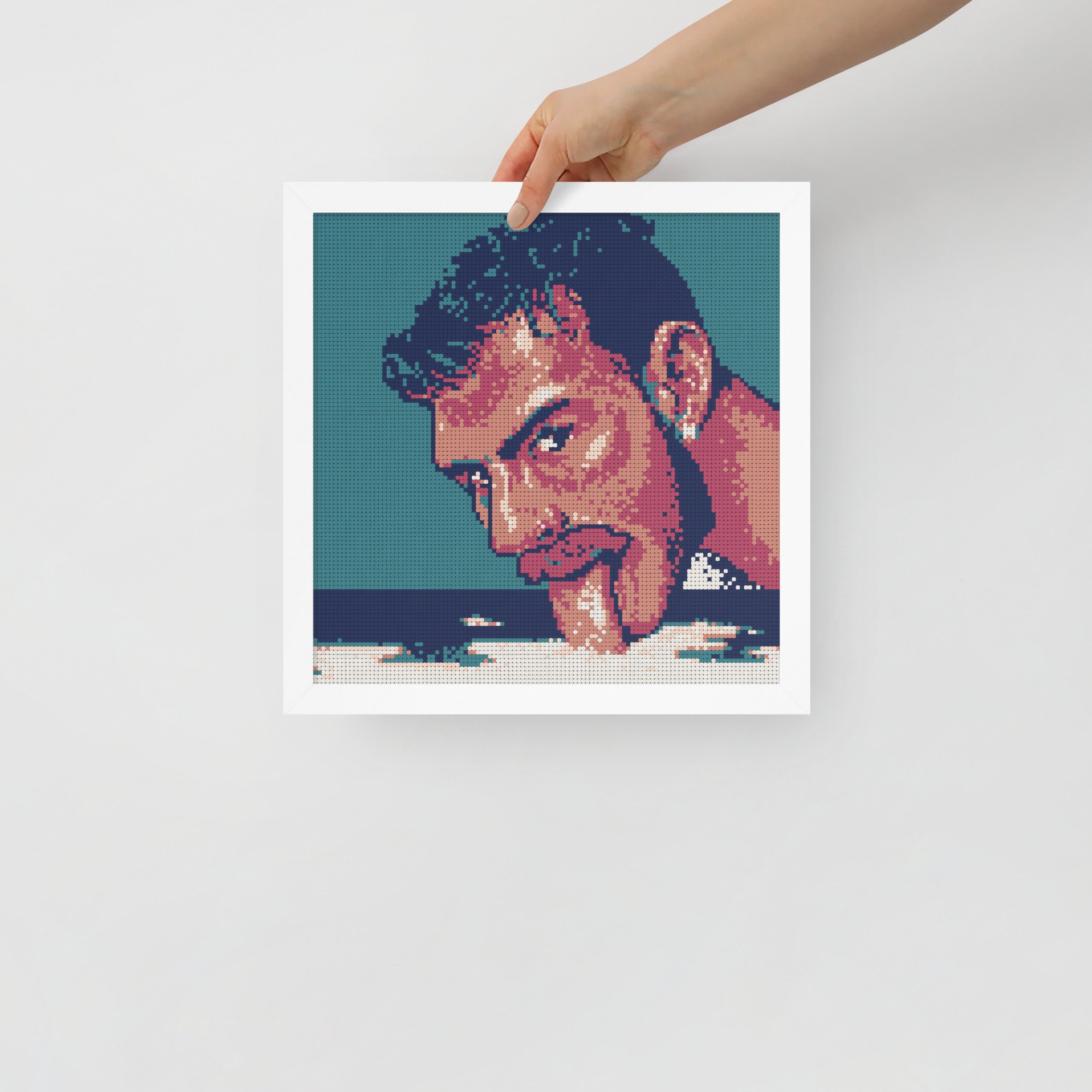 The image is of a faux cross-stitch version of the original "Milk 4" from a series of male portraits. The print is in a white frame against a wall.