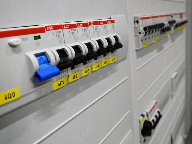 Close-up of electrical circuit breakers in a control panel with labels and switches.