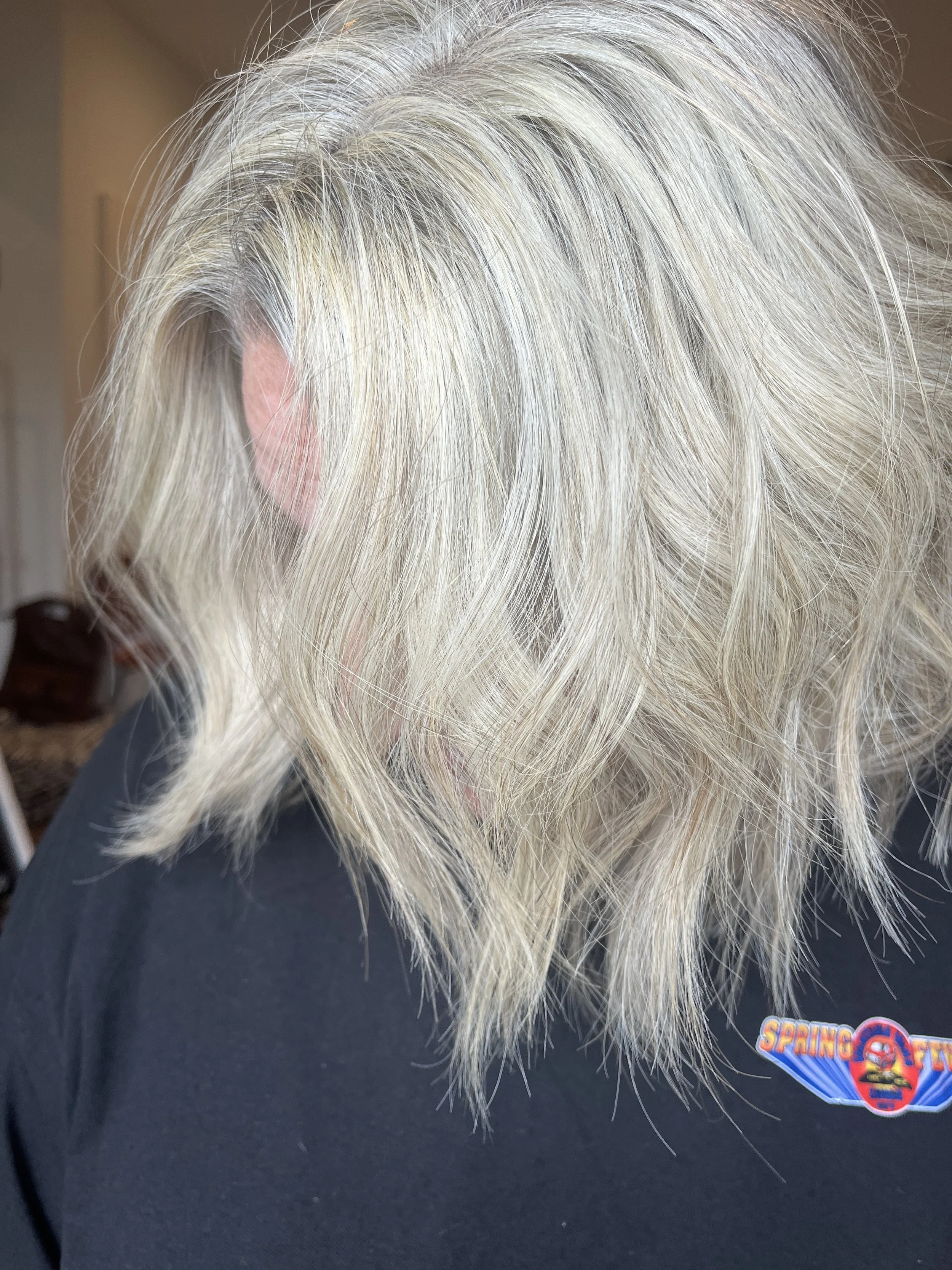 Close-up of a mannequin head with blonde hair styled in loose waves, wearing a black cap with a colorful NASCAR Sprint Cup Series logo.