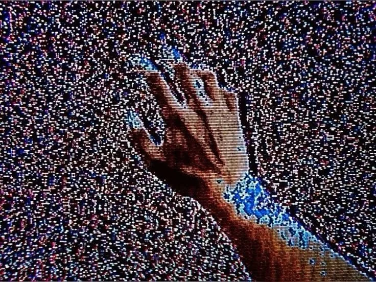 Close-up of a hand with a wrist tattoo reaching out amongst a background of numerous small, colorful static.
