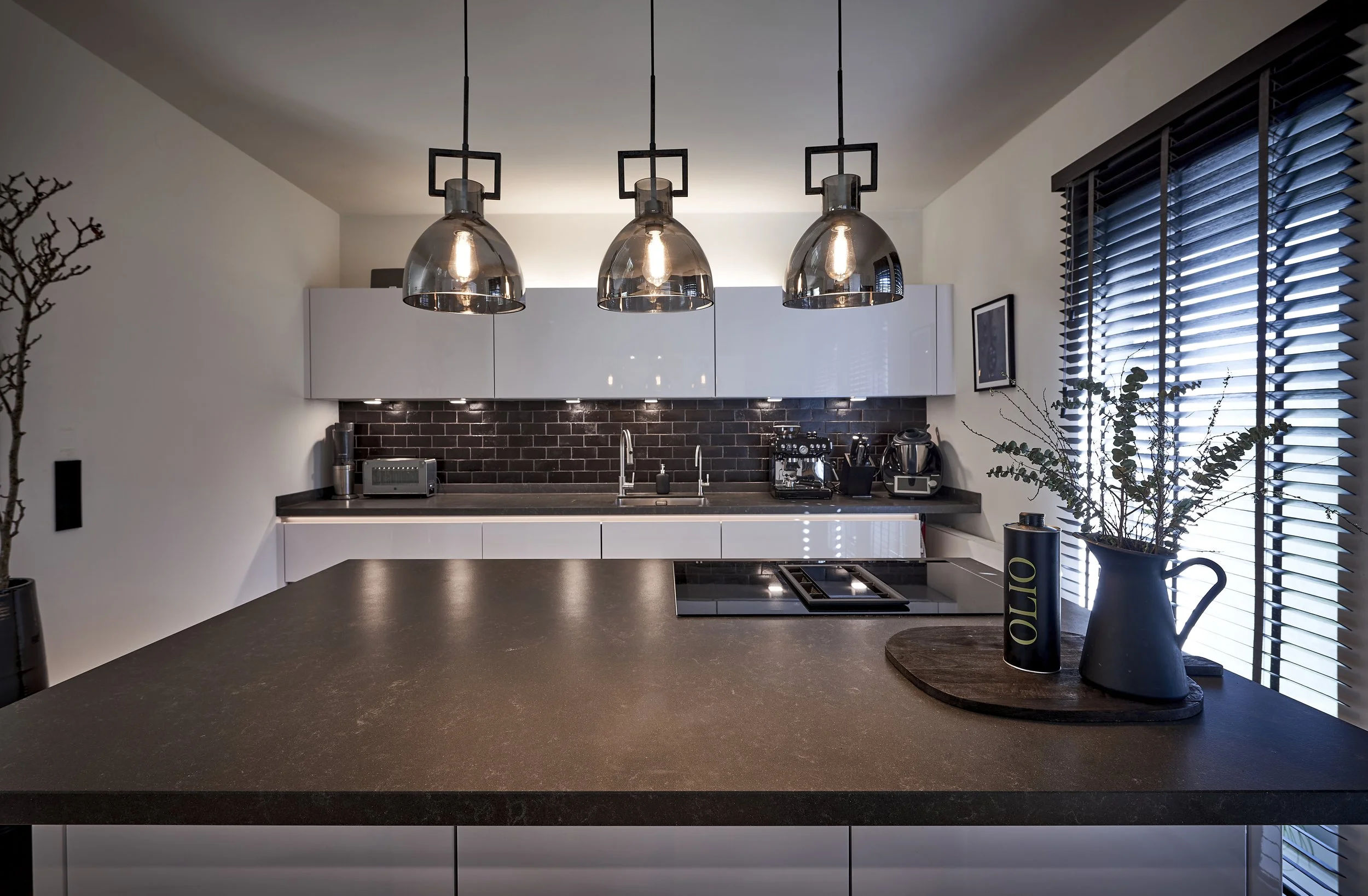 Küche modern schwarz-weiss Mittelblock Arbeitsplatte schwarz Hängeleuchten Holzjalousien 