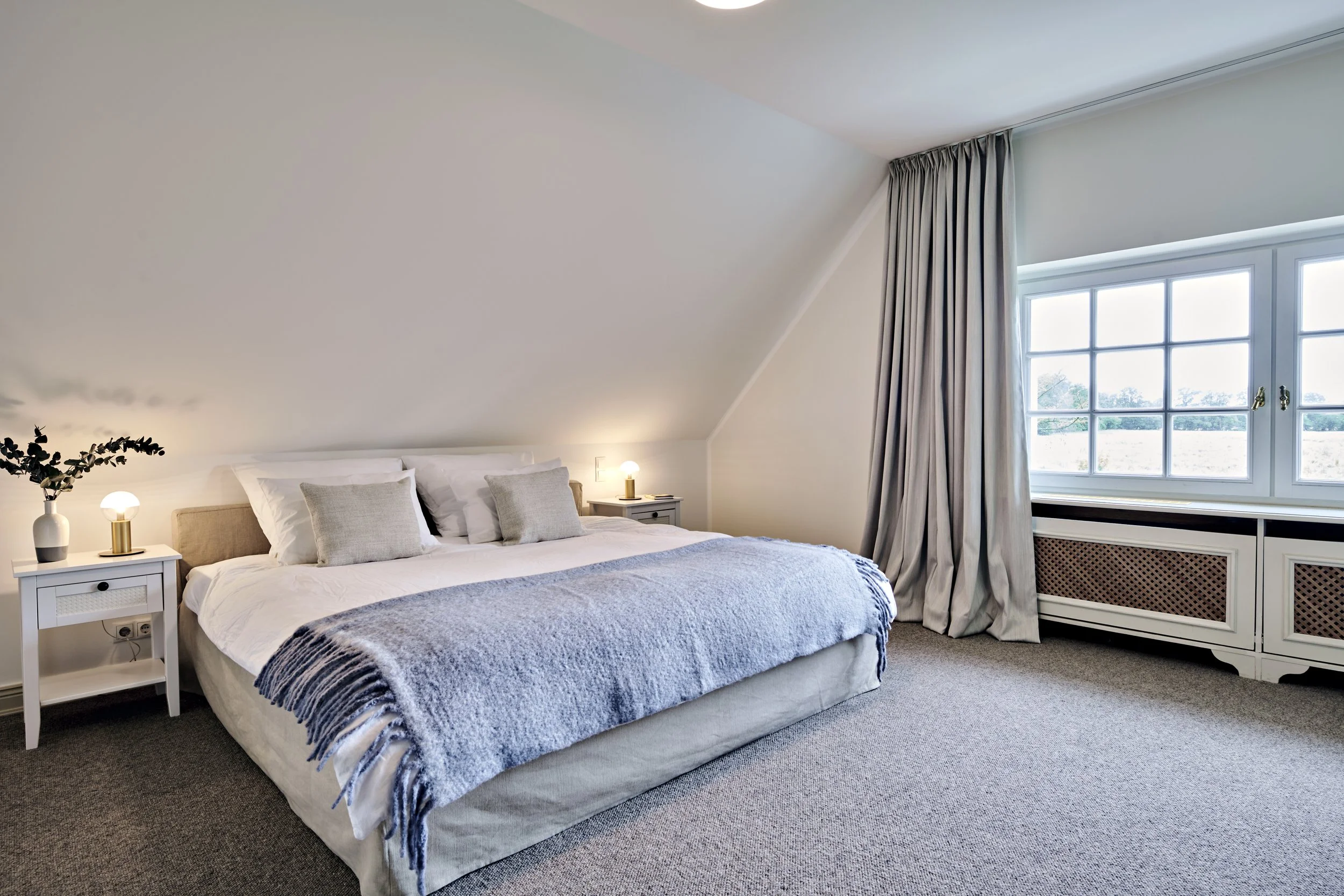 Schlafzimmer Bett Teppichboden beige Landhausstil Vorhänge hell 