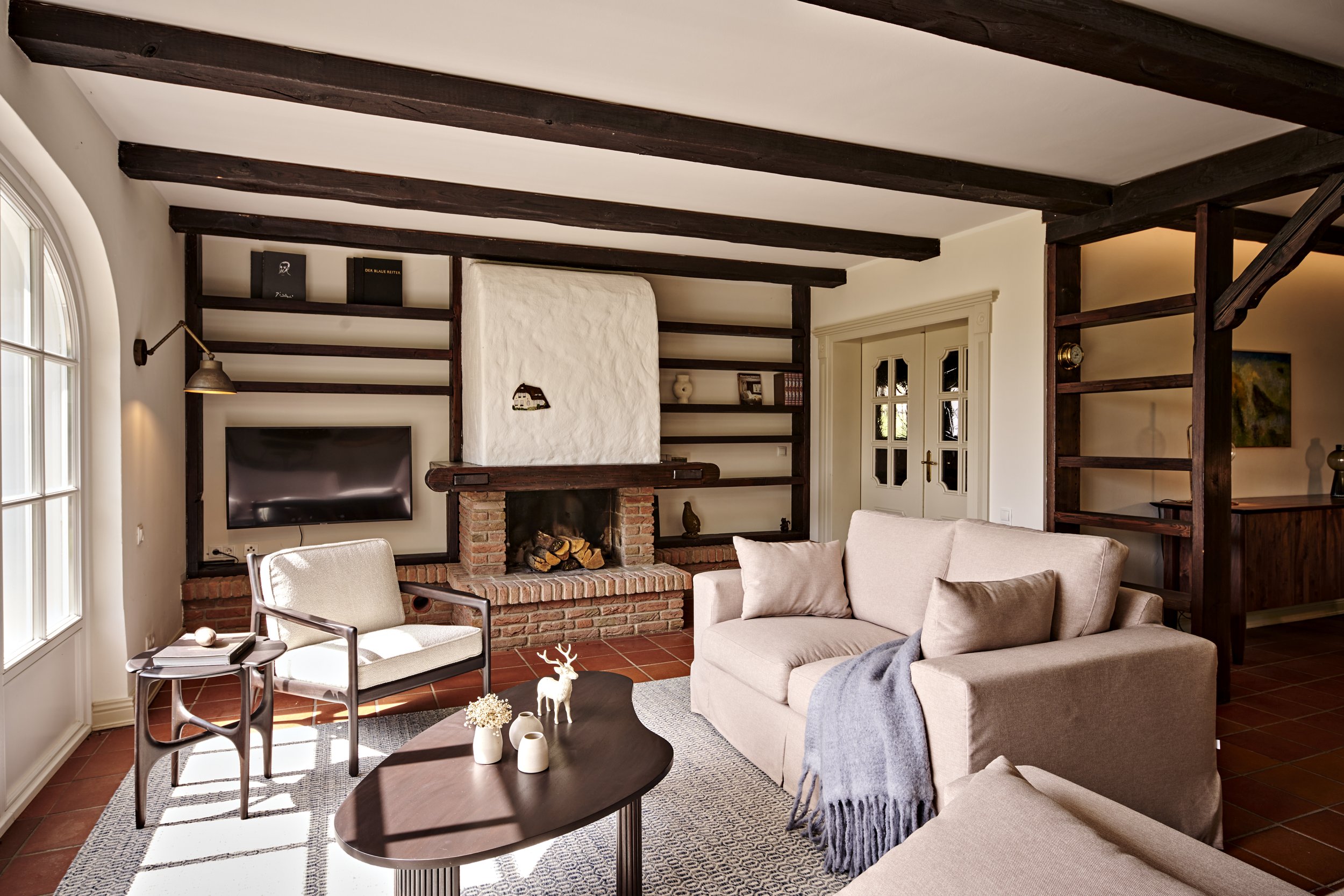 Wohnzimmer Sofas beige Holzbalken dunkelbraun offener Kamin Tische Ethnicraft Landhausstil