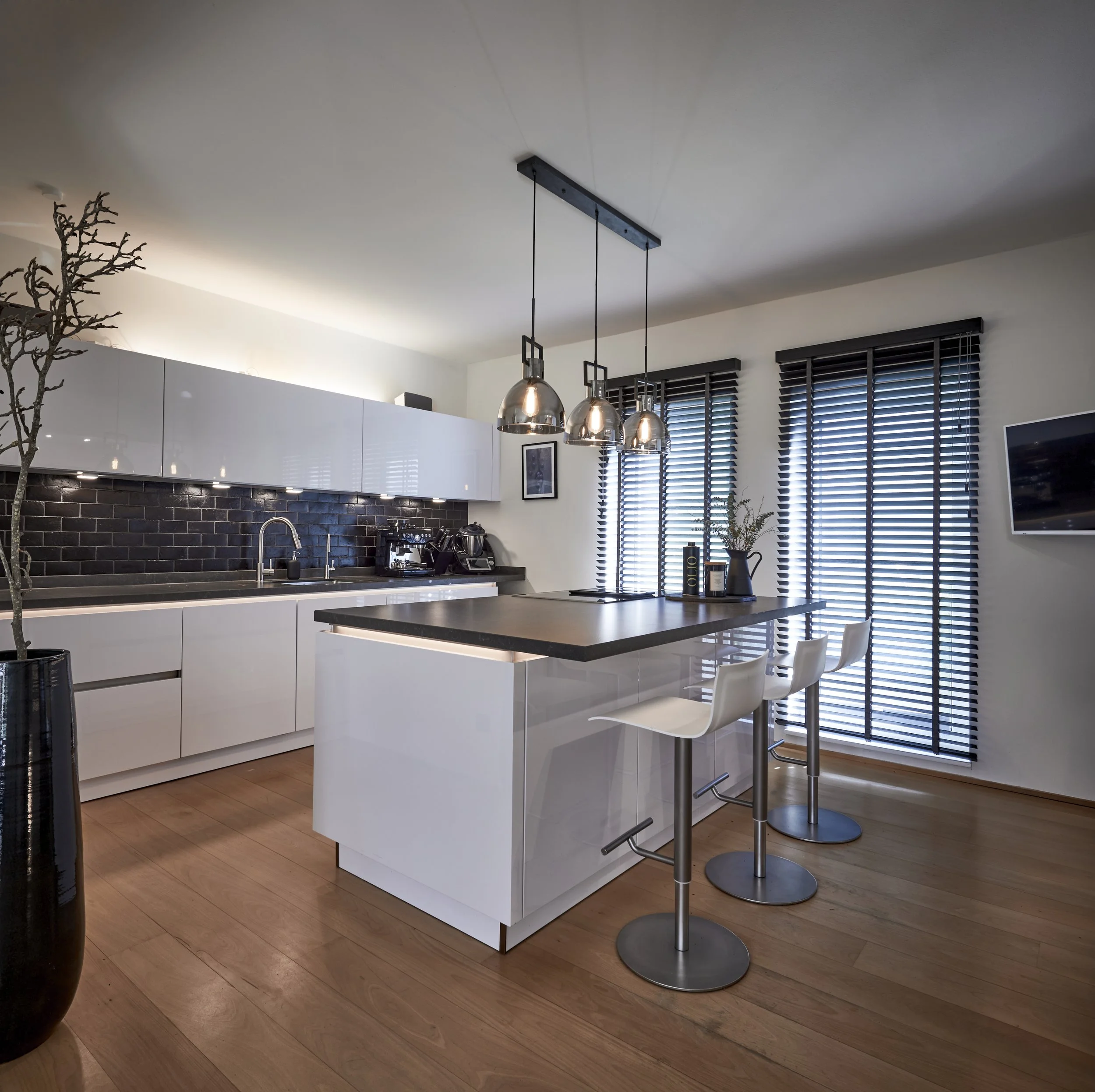 Küche modern schwarz-weiss Mittelblock Arbeitsplatte schwarz Fronten weiss Holzboden Barstühle 