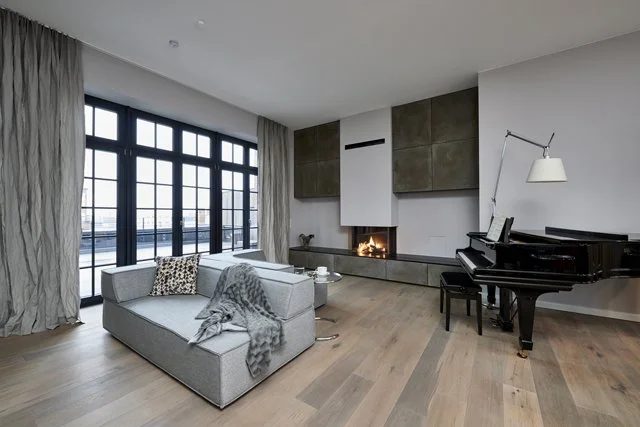 Wohnzimmer Penthouse Kamin Loftfenster Klavier hellgraues Cor Sofa