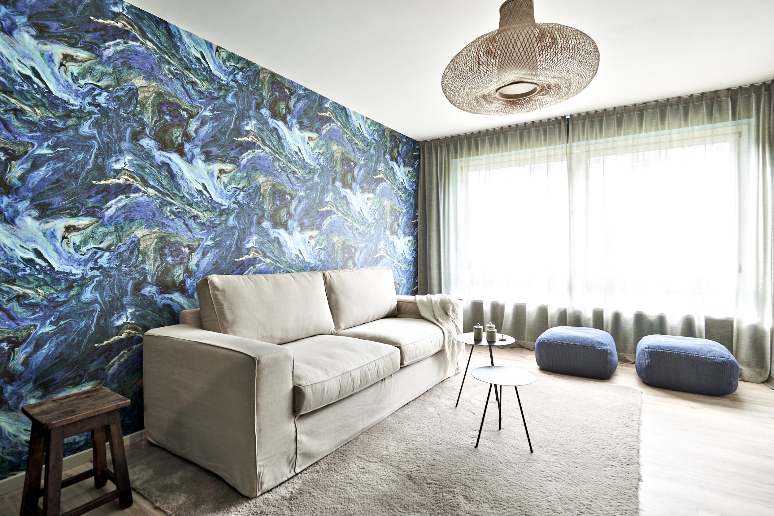 Wohnzimmer Tapete blau grün Chivasso Sofa Teppich beige Hocker blau Beistelltische more