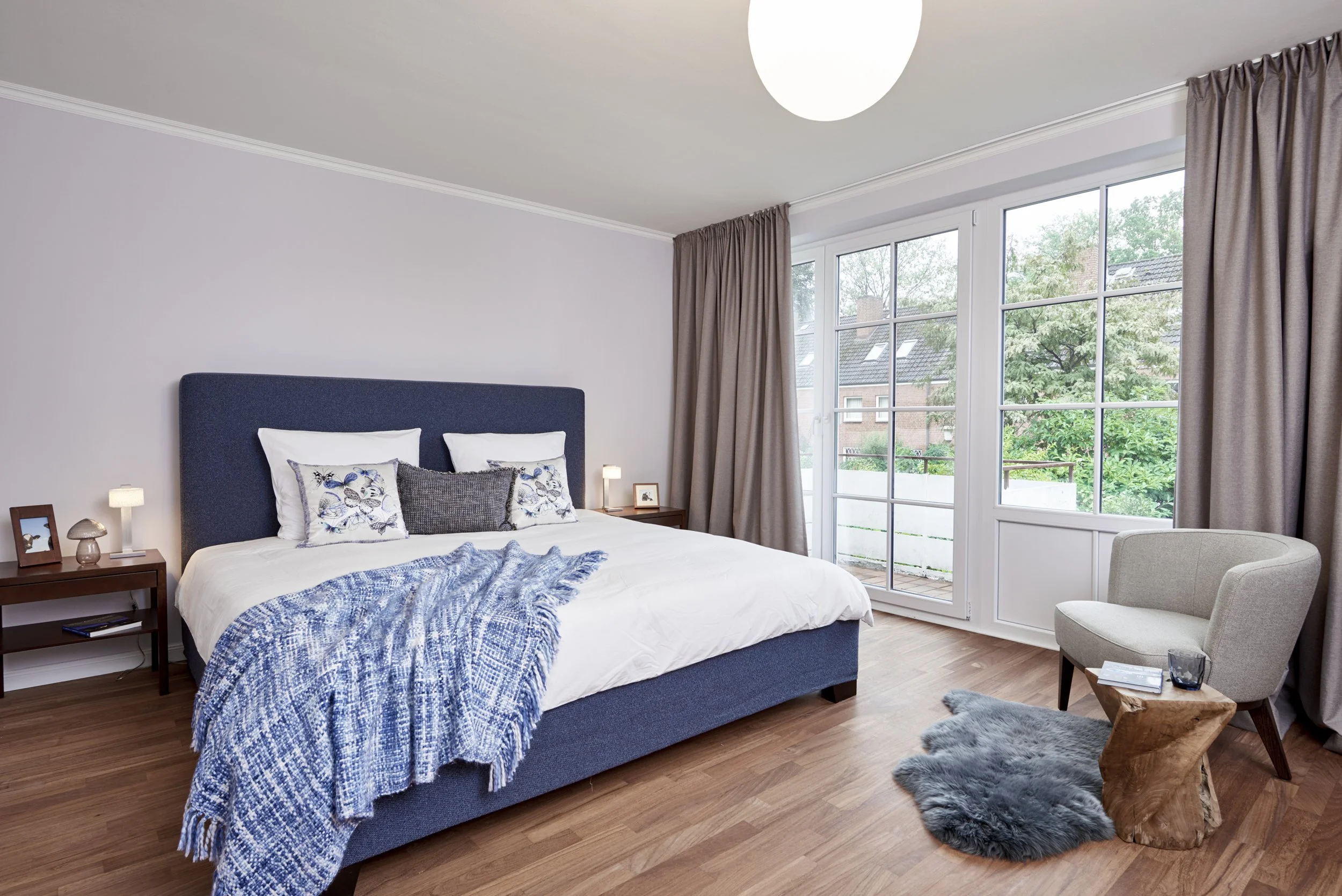 Schlafzimmer Bett Signet blau gepolstert Holzboden Vorhänge braun Romo