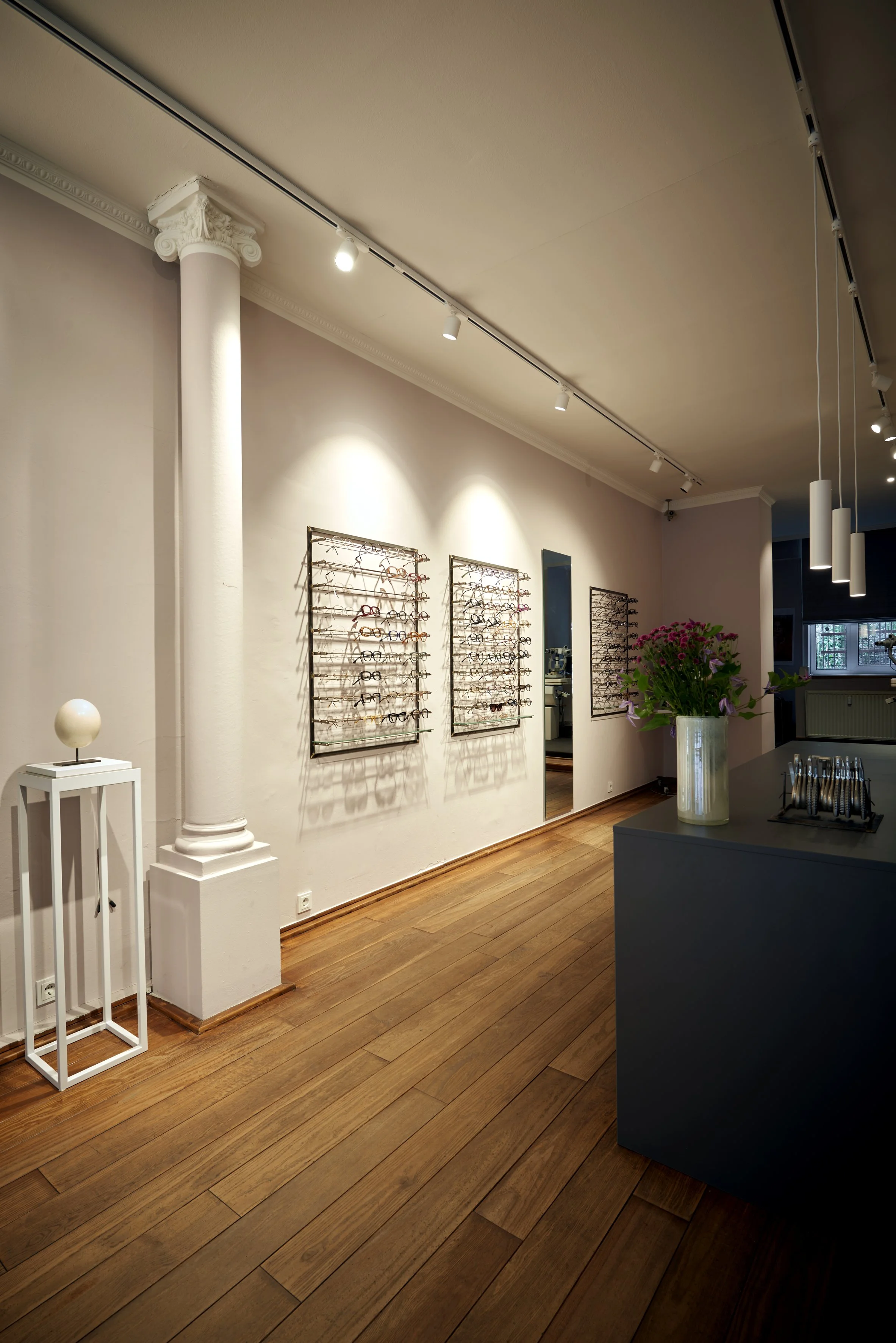Brillenfachgeschäft Augenblick Holzdielenboden Verkaufstresen anthrazit Schienensystem weiss Beleuchtung Säule weiss