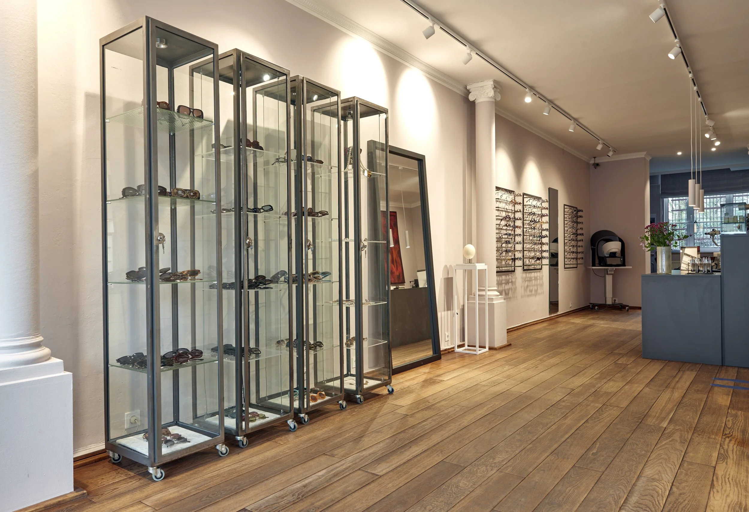 Brillenfachgeschäft Augenblick Vitrinen Glas Metall Schienensystem weiss Beleuchtung Holzdielenboden 