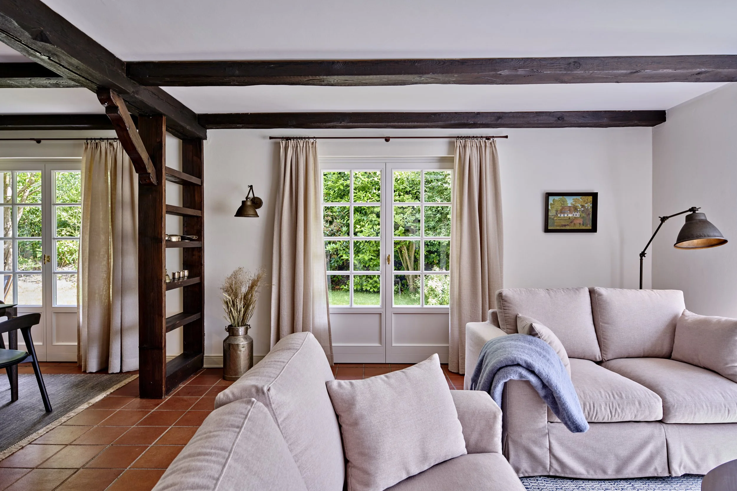 Wohnzimmer Sofa beige Holzbalken dunkelbraun Vorhänge Leinen Landhausstil