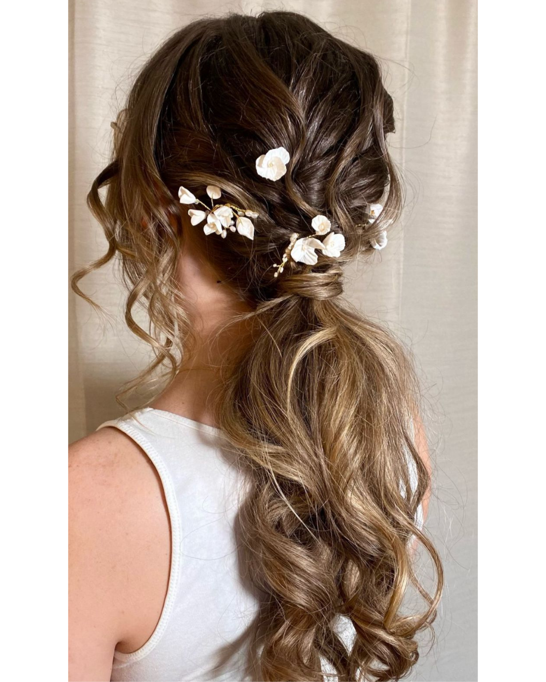 Wavy Boho Hairstyle tied up low with floral hair accessories.